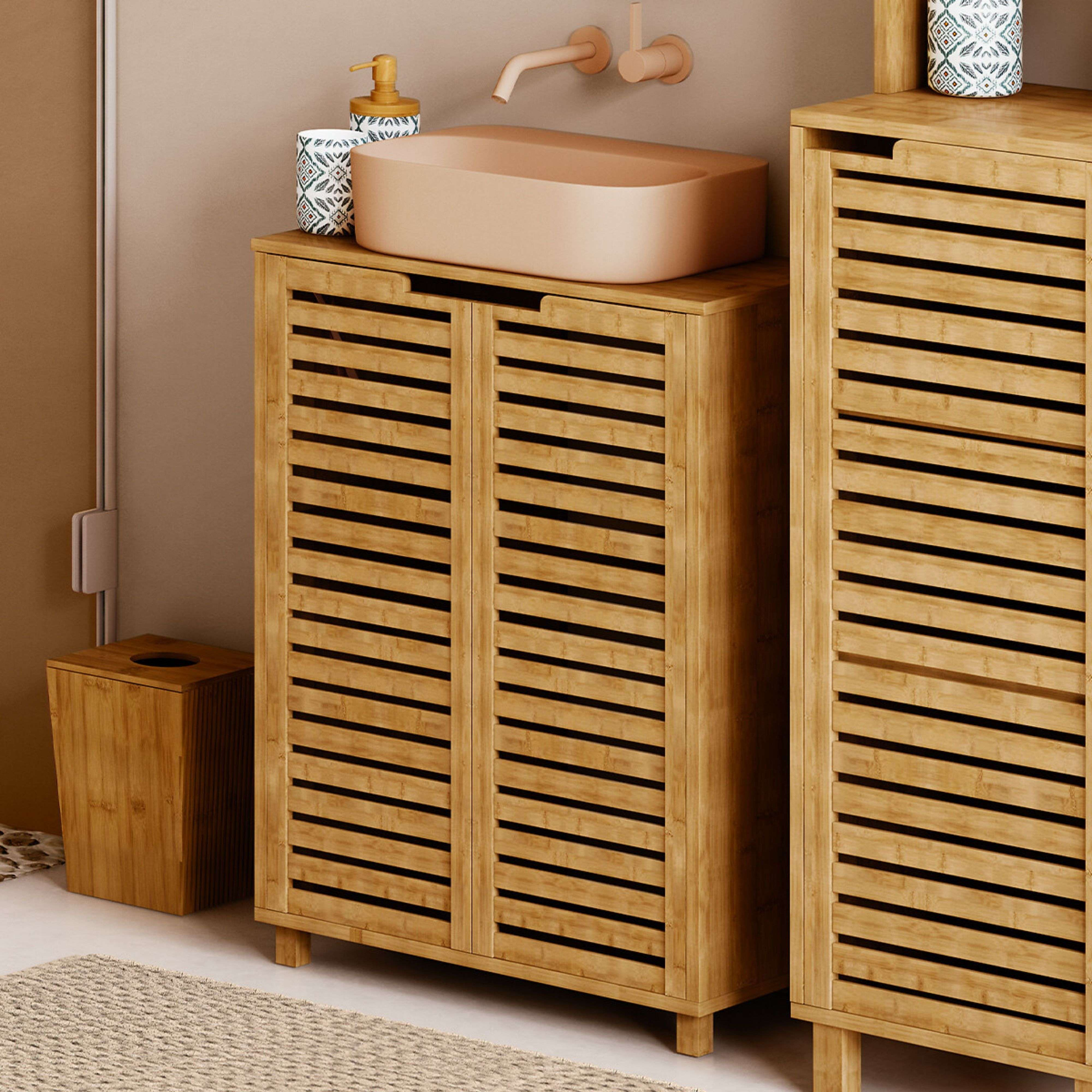 Mueble de baño de bambú con puertas de lamas, lavabo beige y grifo de pared.