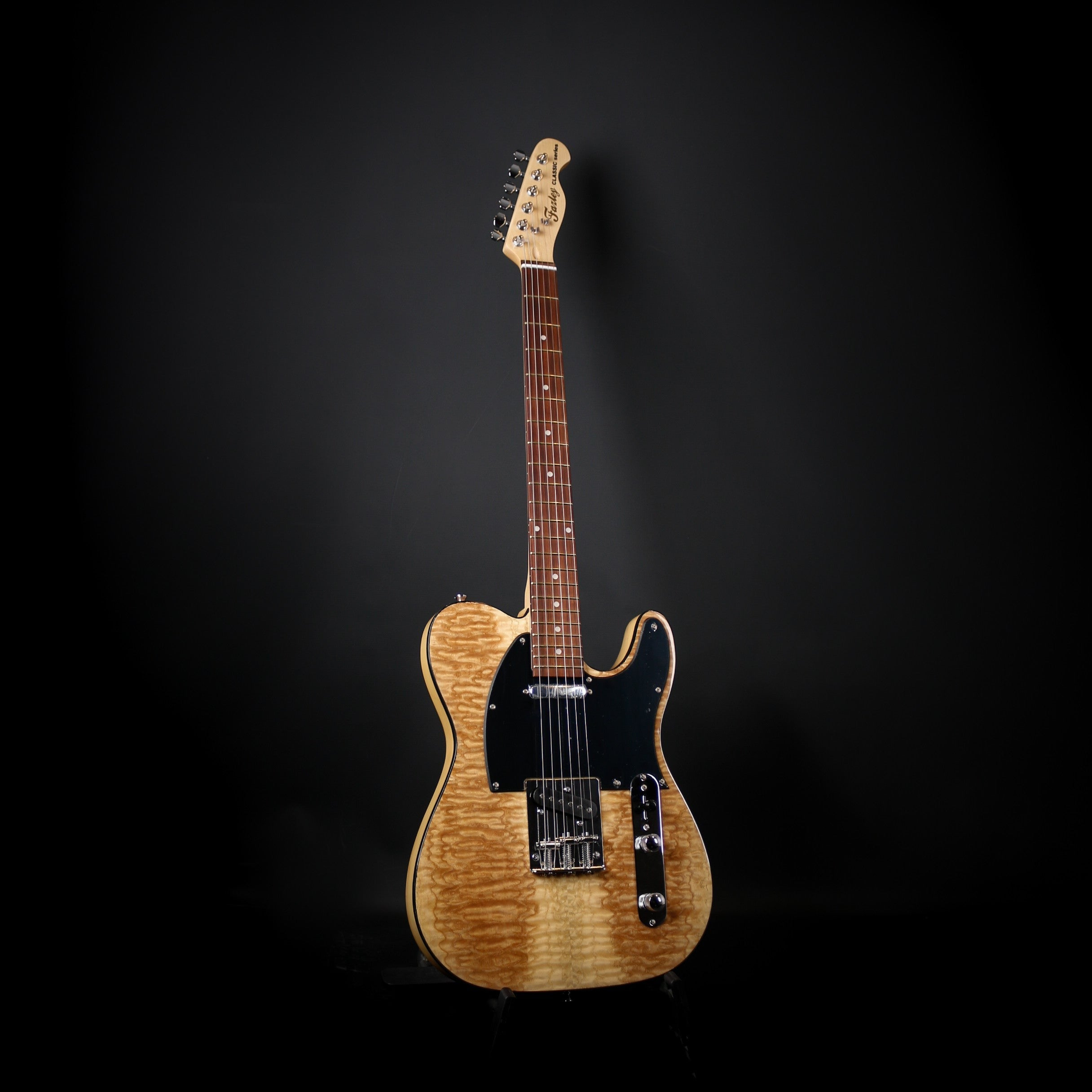 Een blonde Telecaster-stijl elektrische gitaar met een zwart slagplaatje.