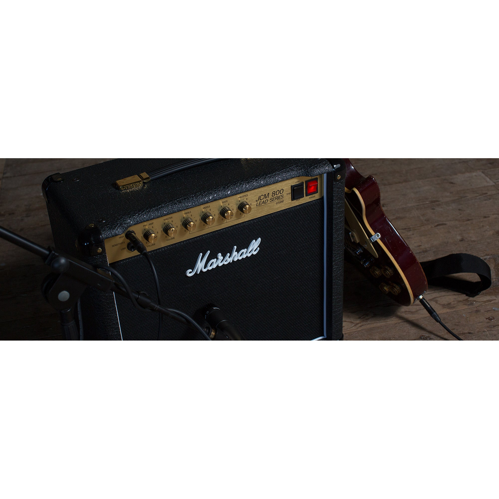 Een Marshall JCM 800 gitaarversterker met bedieningselementen en een gitaar ernaast.