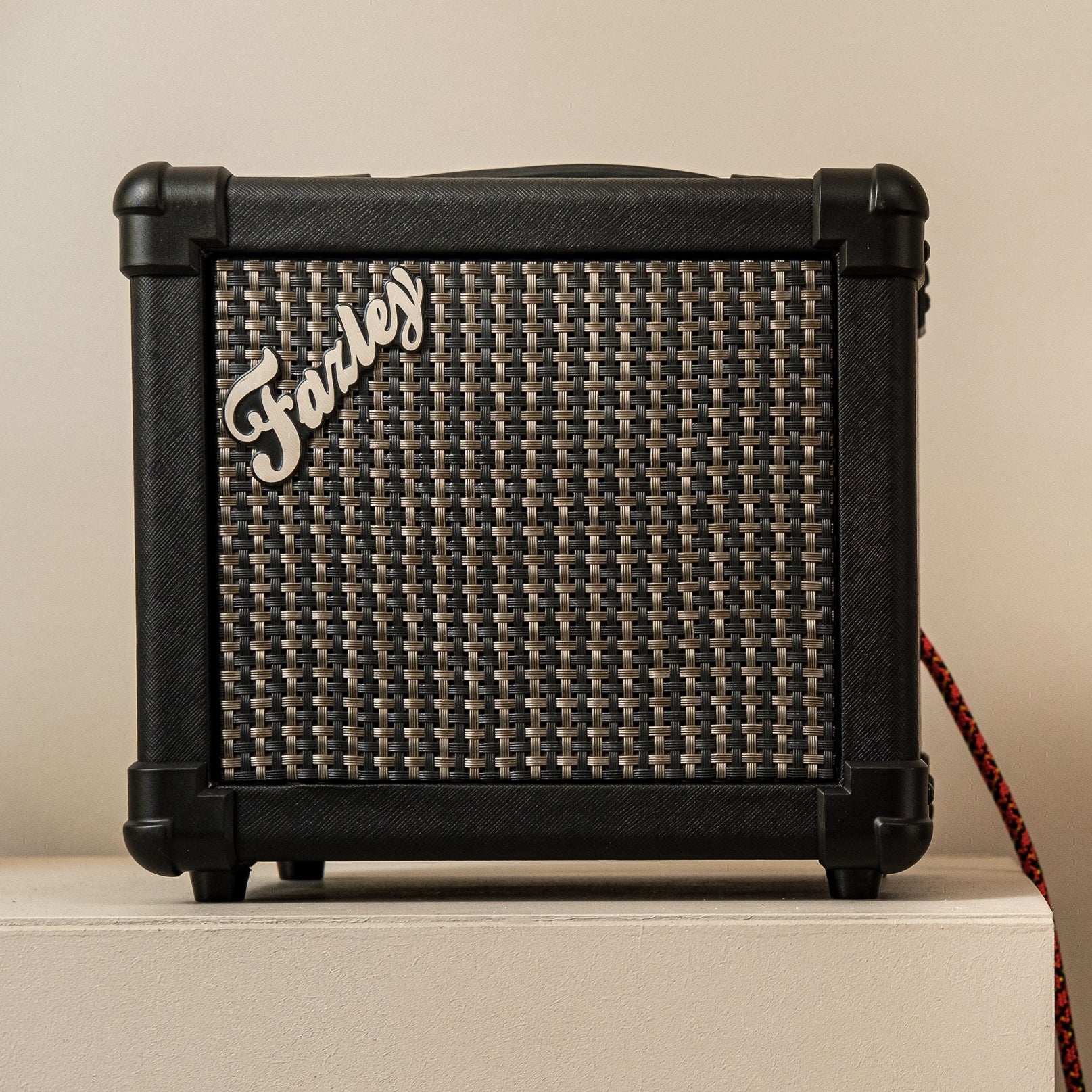 Zwarte gitaarversterker met stoffen grill en "Farley" logo.