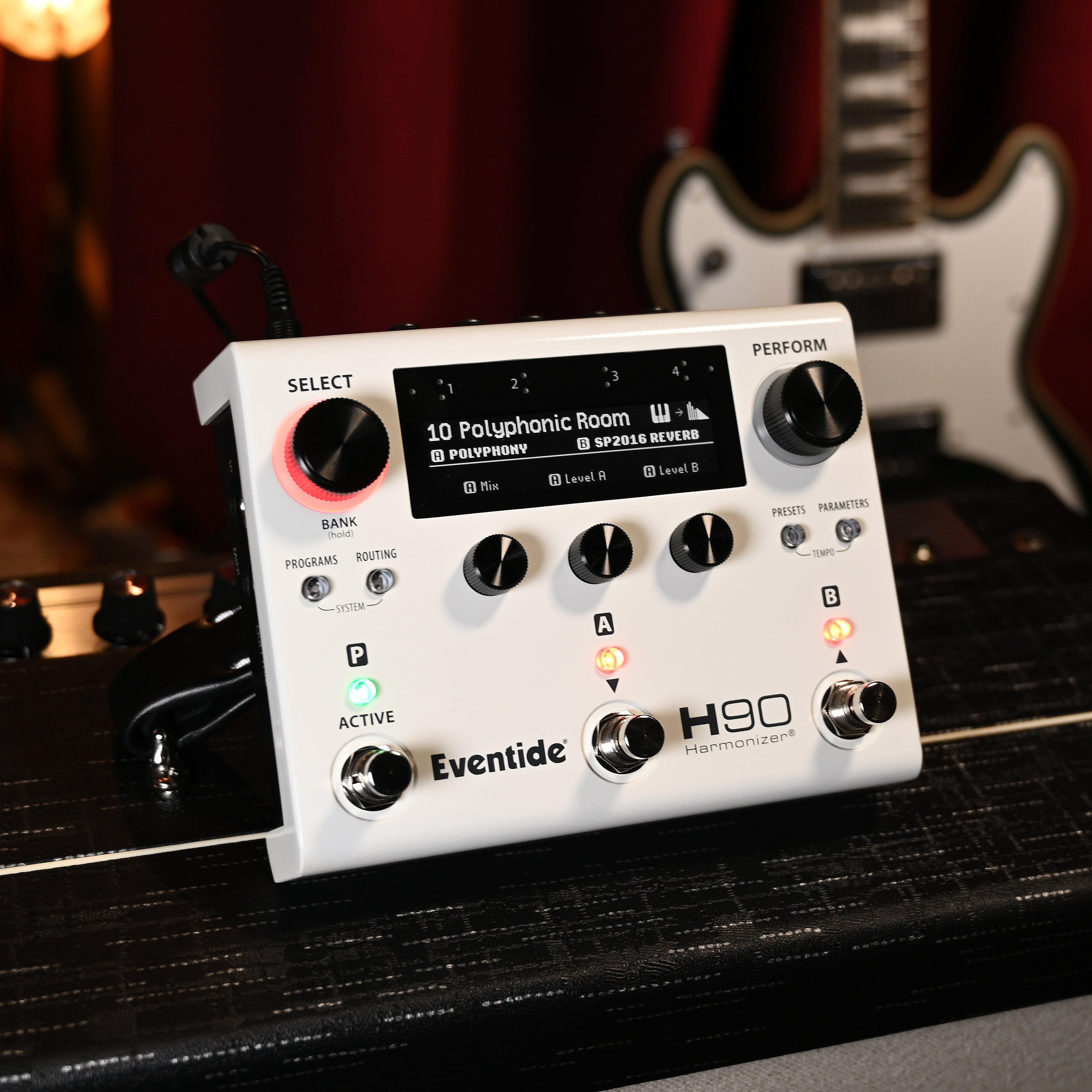 Een wit Eventide H90 Harmonizer pedaal staat op een gitaarversterker met een gitaar erachter.