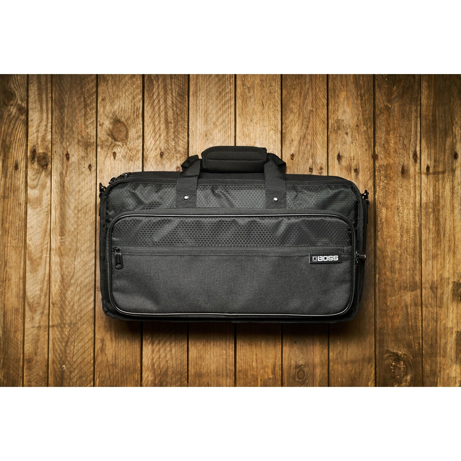 Zwarte tas met handvatten en ritsen op een houten achtergrond.
