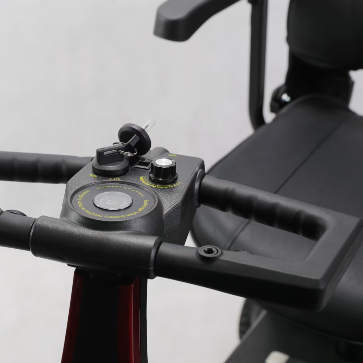 Zbliżenie na sterowanie skutera inwalidzkiego z kluczykiem i pokrętłami.