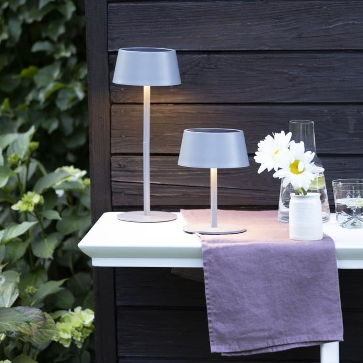Zwei graue Lampen stehen auf einem Tisch mit einer lila Tischdecke.