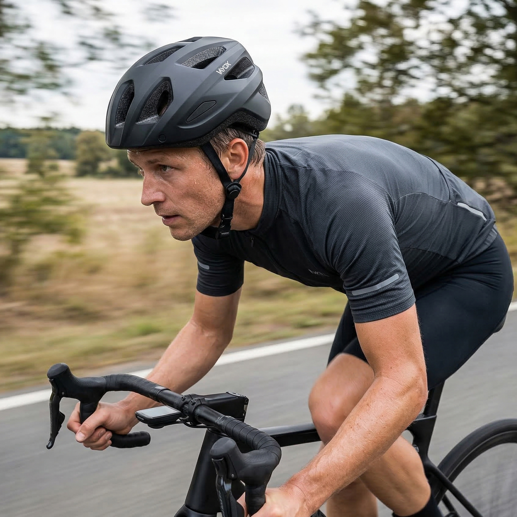 Mężczyzna jedzie rowerem po drodze z drzewami w tle.