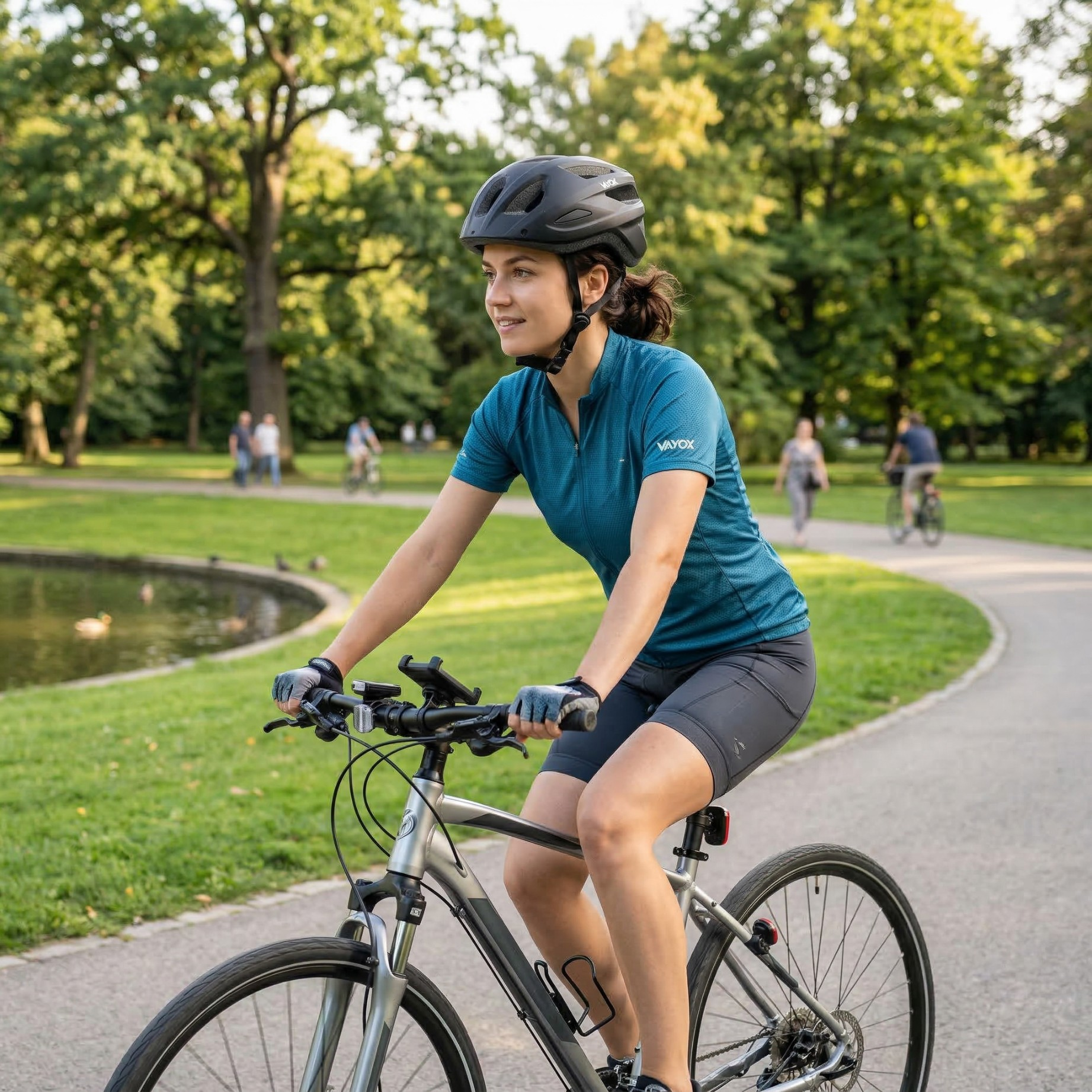 Kobieta jedzie rowerem w parku z oczkiem wodnym i drzewami.