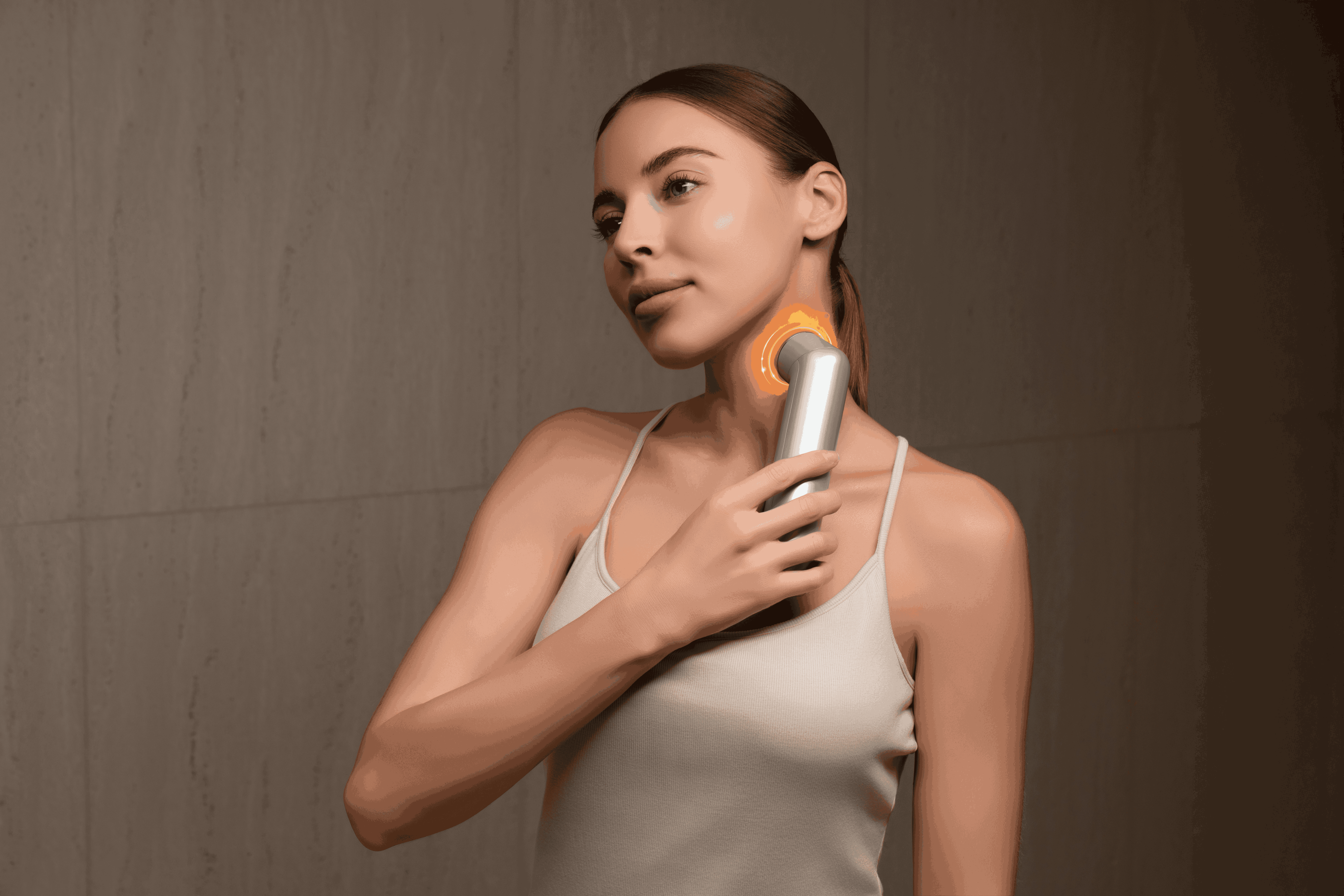 Una donna usa un dispositivo per la cura della pelle sul collo, che brilla di arancione.