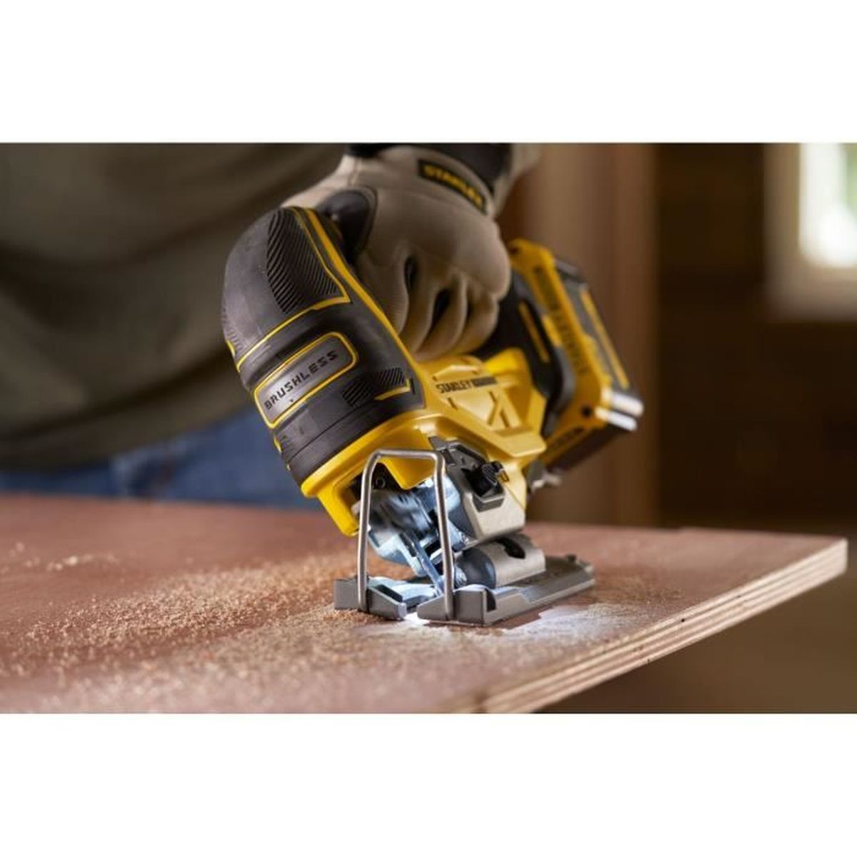 Eine Hand in einem Handschuh bedient einen gelben und schwarzen Stichsäge auf Holz.