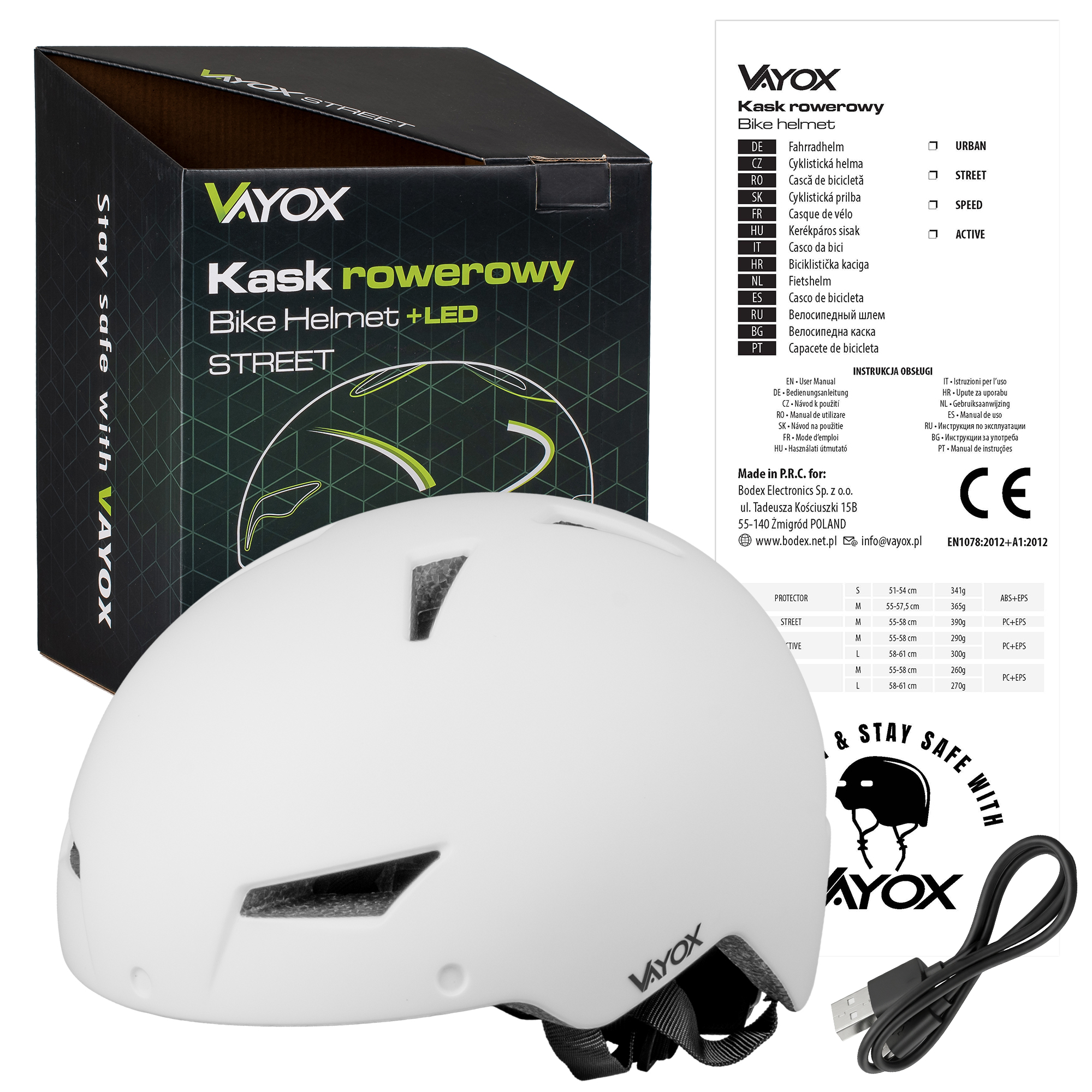 Biały kask rowerowy Vayox leży obok pudełka i kabla USB.