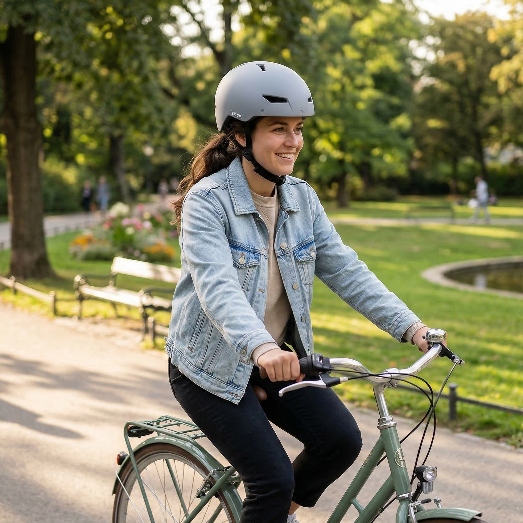 Kobieta w kasku jedzie rowerem w parku.