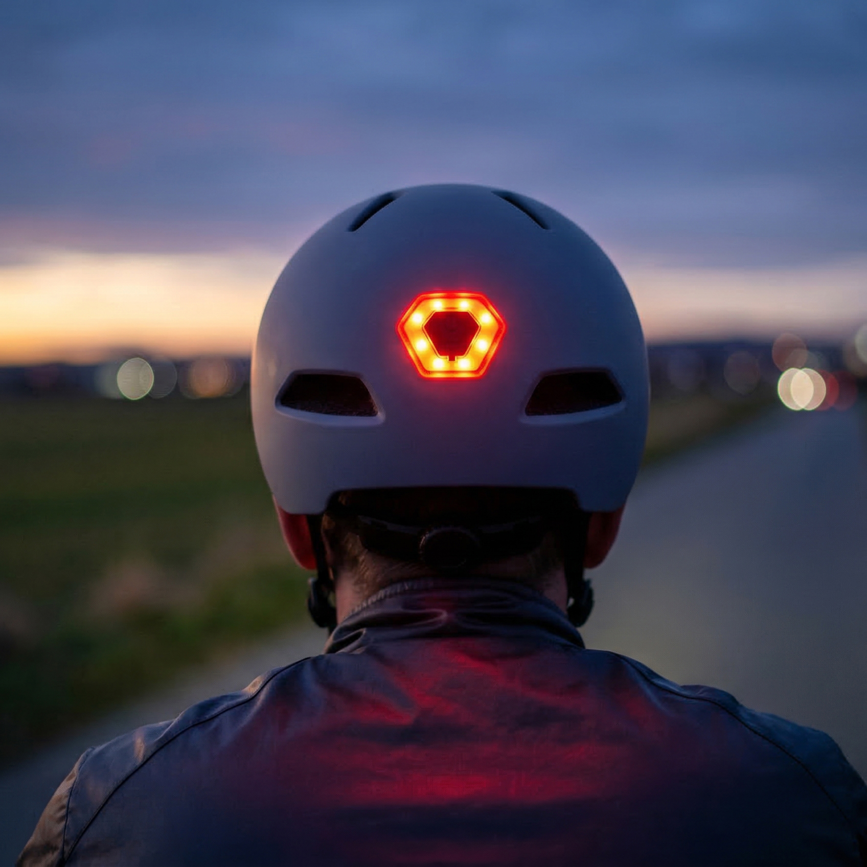 Widok z tyłu kasku z jasnoczerwonym światłem tylnym o zmierzchu.