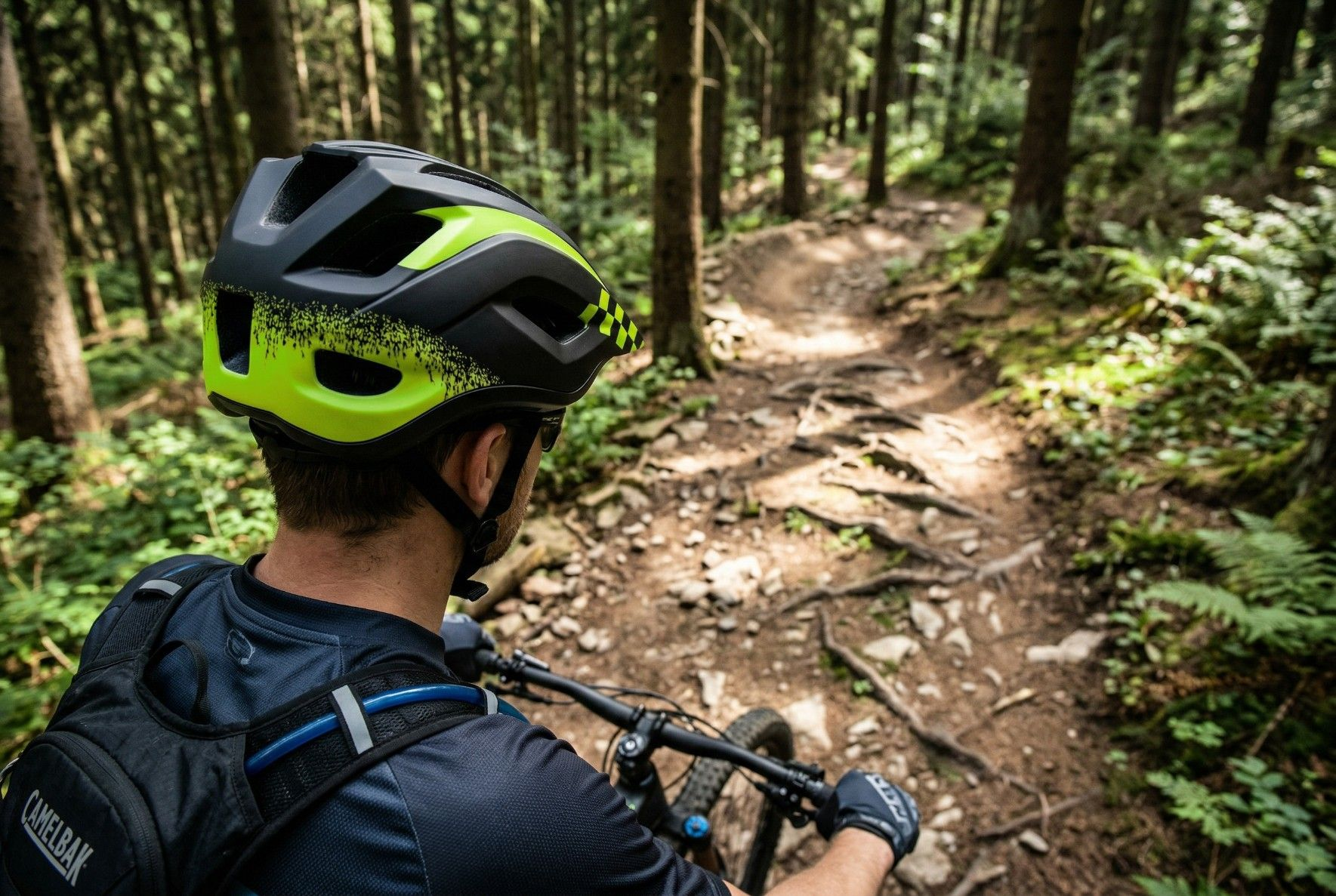 Kolarz w kasku na leśnej ścieżce z korzeniami i drzewami.