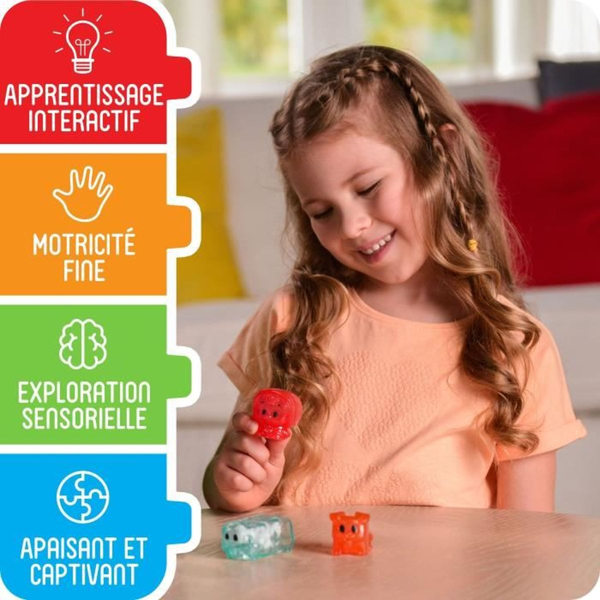 Ein Mädchen hält ein rotes Spielzeug, zwei weitere liegen auf dem Tisch.