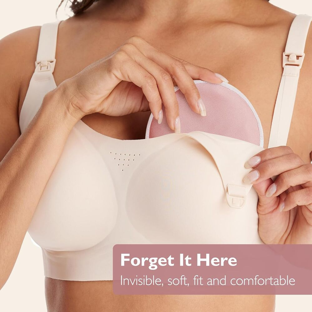 Una mano inserisce un pad rosa in un reggiseno color crema.