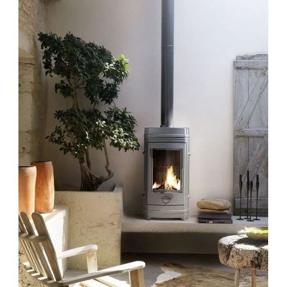 Ein moderner Kamin mit brennendem Feuer, daneben ein Baum und ein Stuhl.