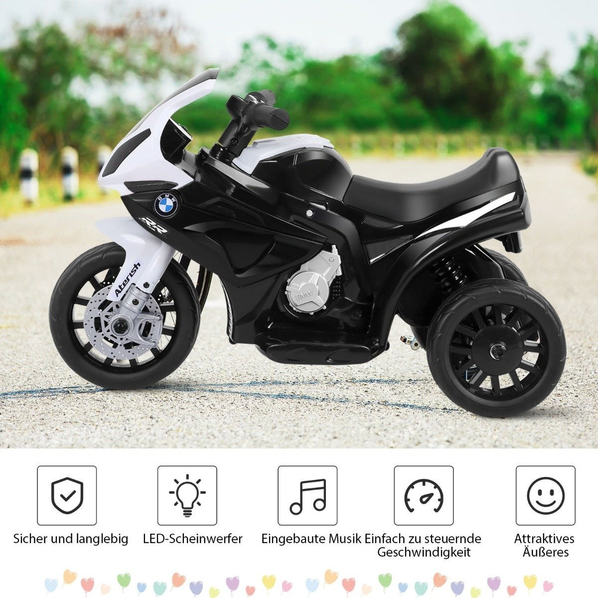 A black and white BMW children's ride-on motorcycle with three wheels outdoors.