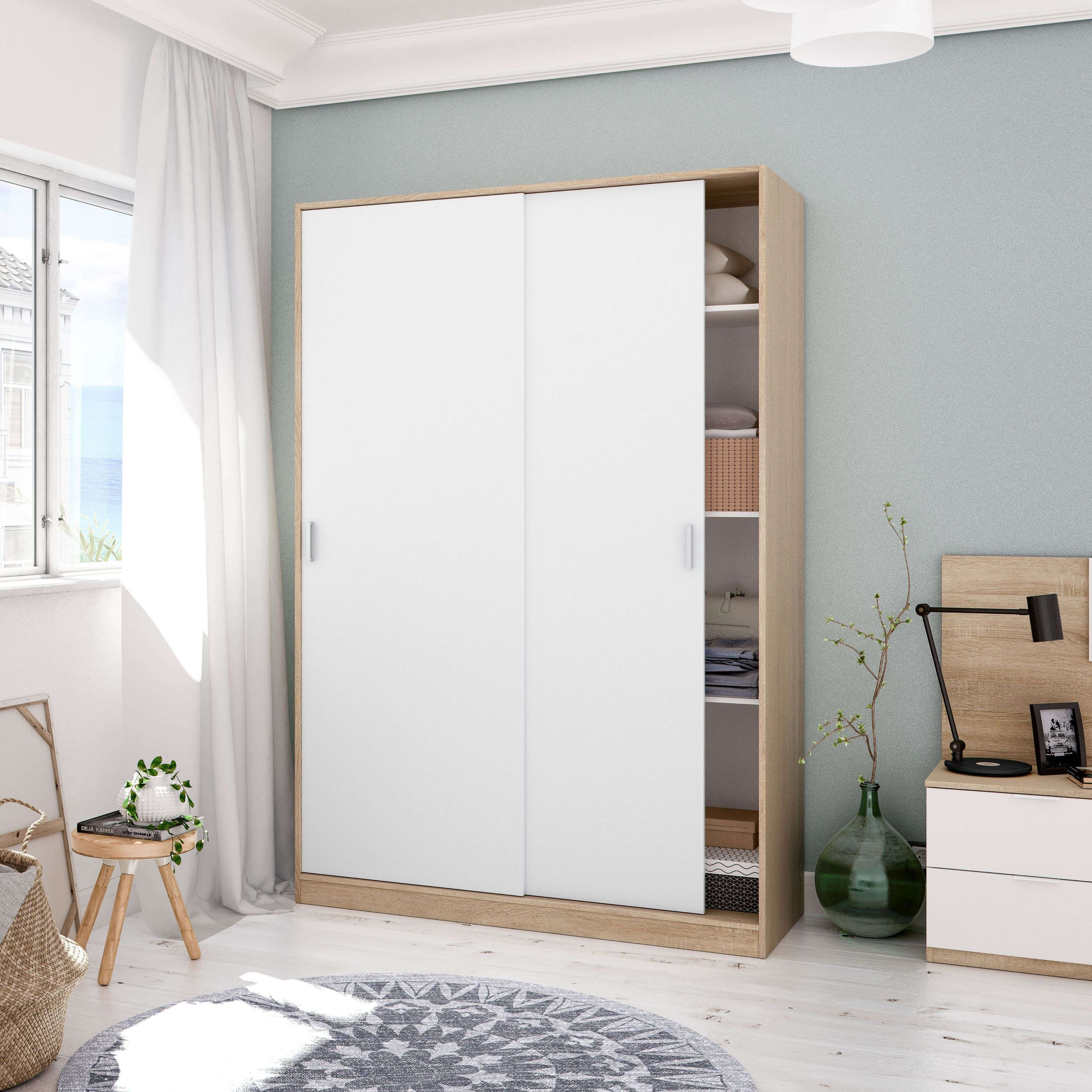 Un dormitorio con armario blanco de puertas correderas, mesita y ventana.