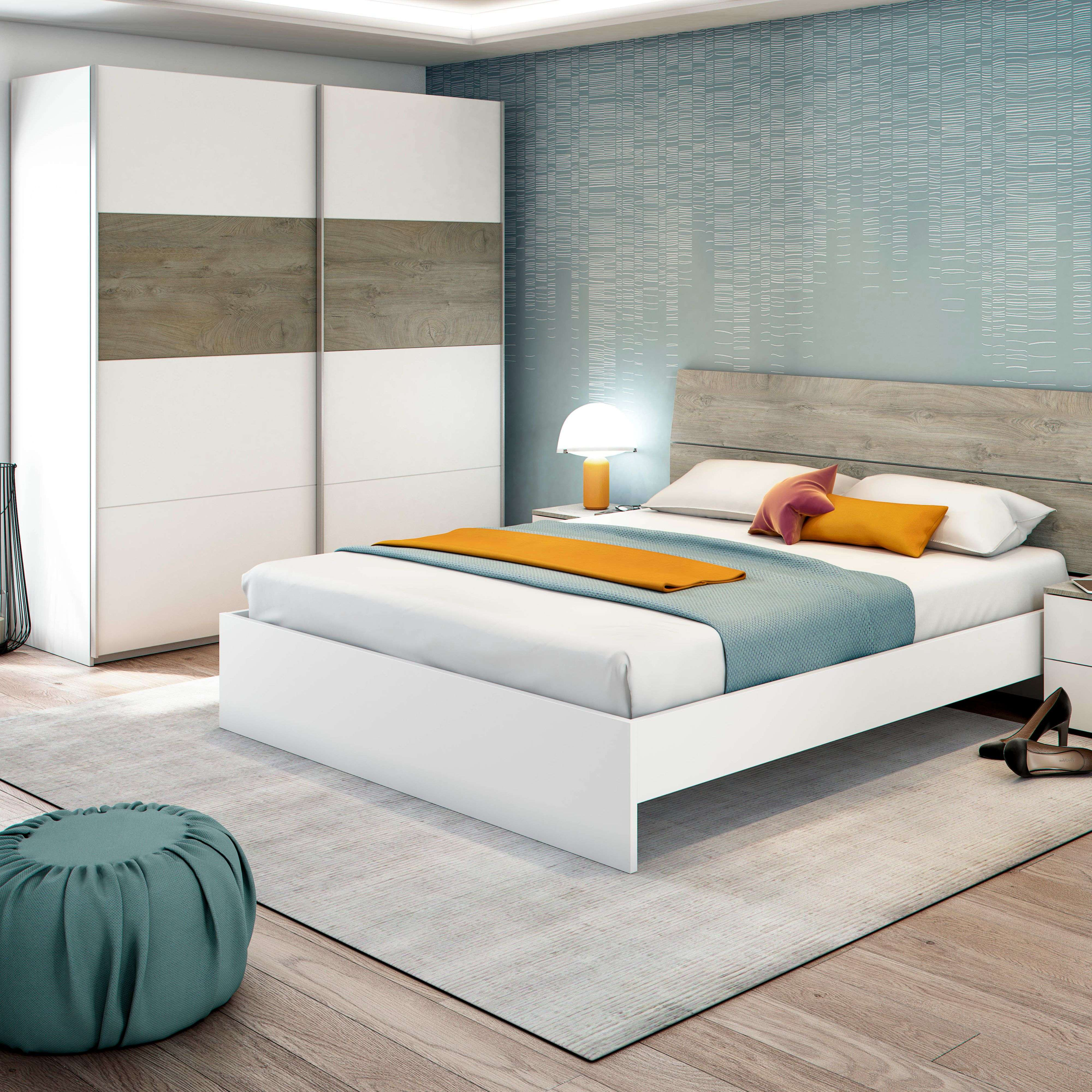 Un dormitorio con cama blanca, cabecero de madera, armario y papel pintado azul.
