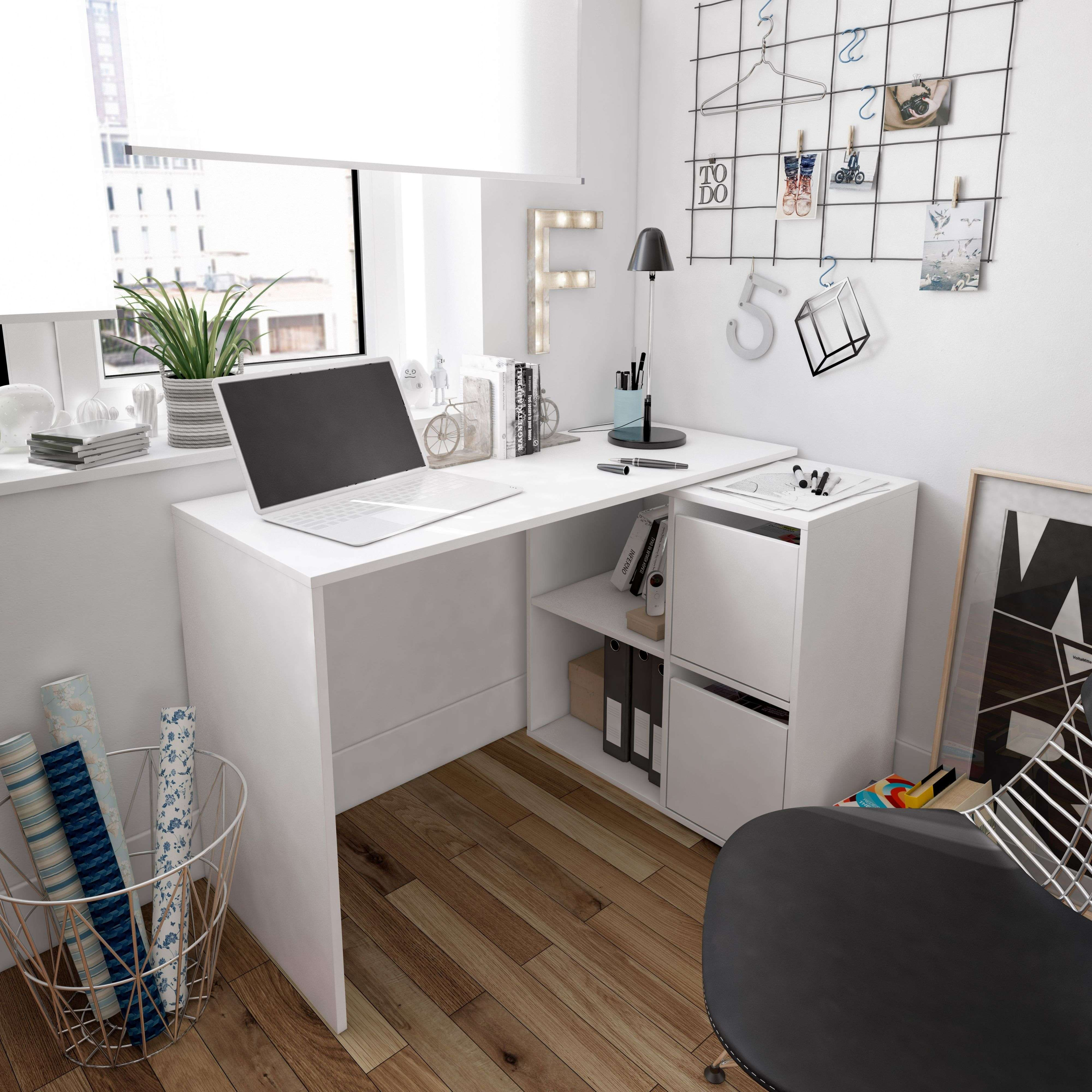 Un escritorio blanco con portátil, planta y decoraciones.