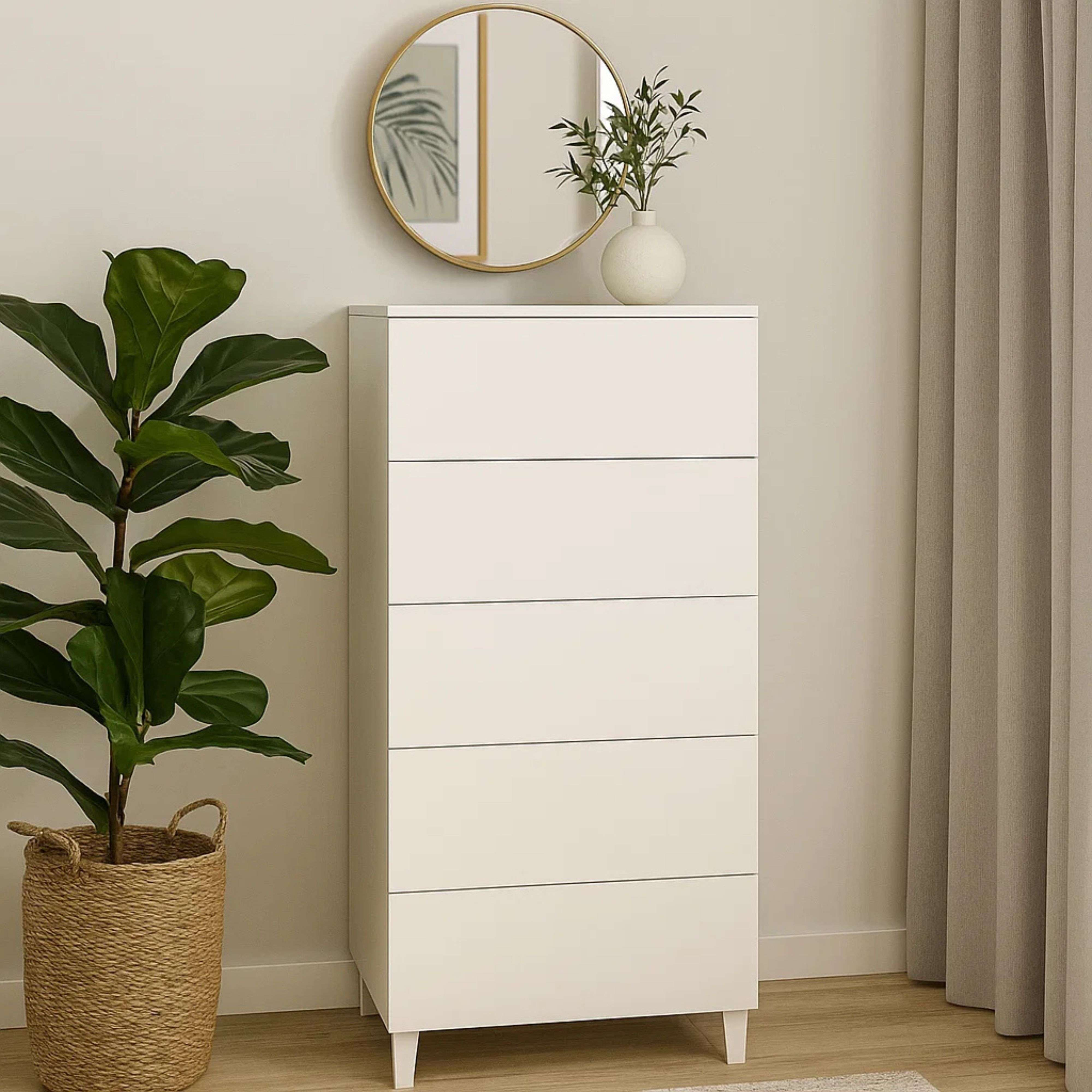 Una cómoda blanca de seis cajones junto a una planta en maceta.