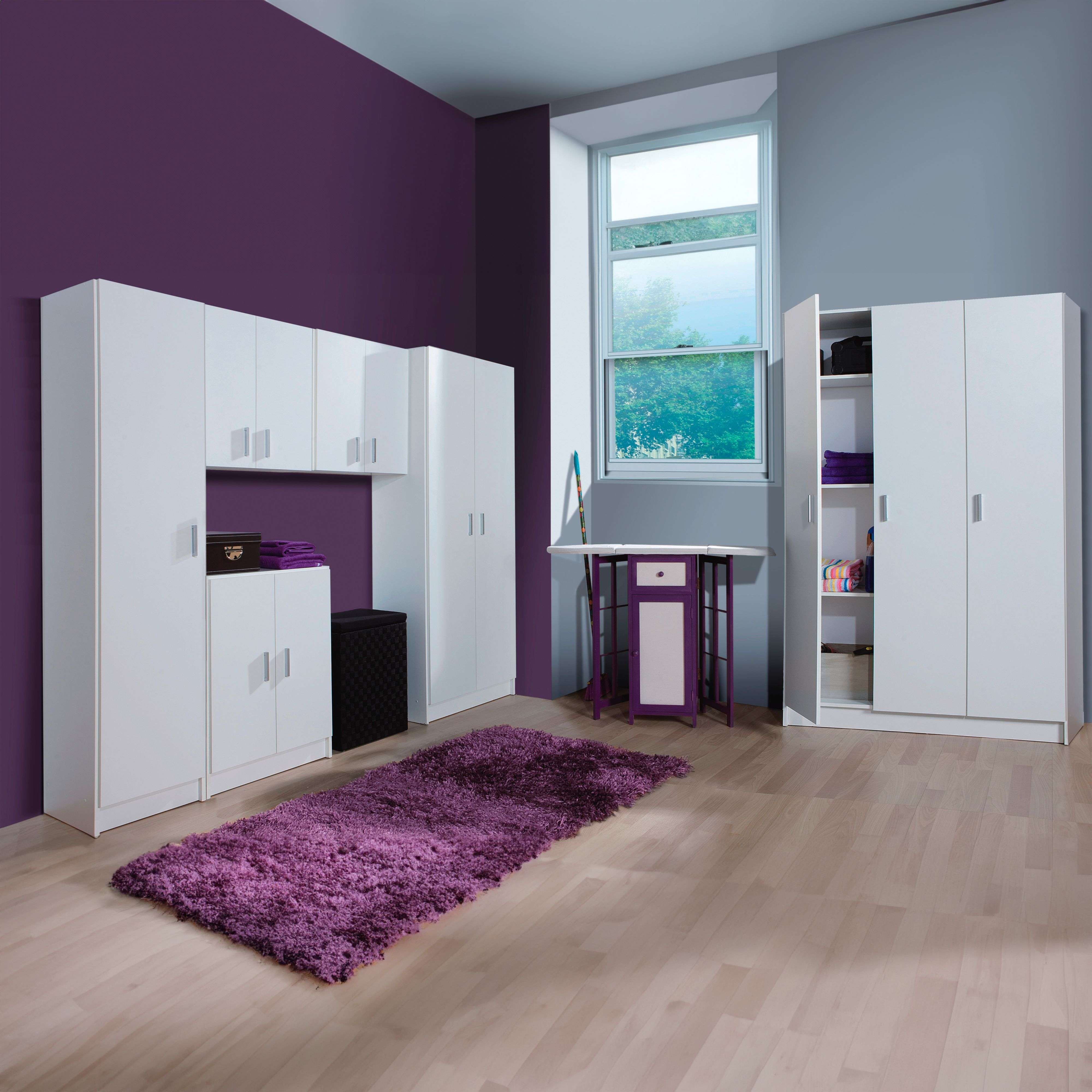 Una habitación con armarios blancos, un escritorio, una alfombra morada y una ventana.
