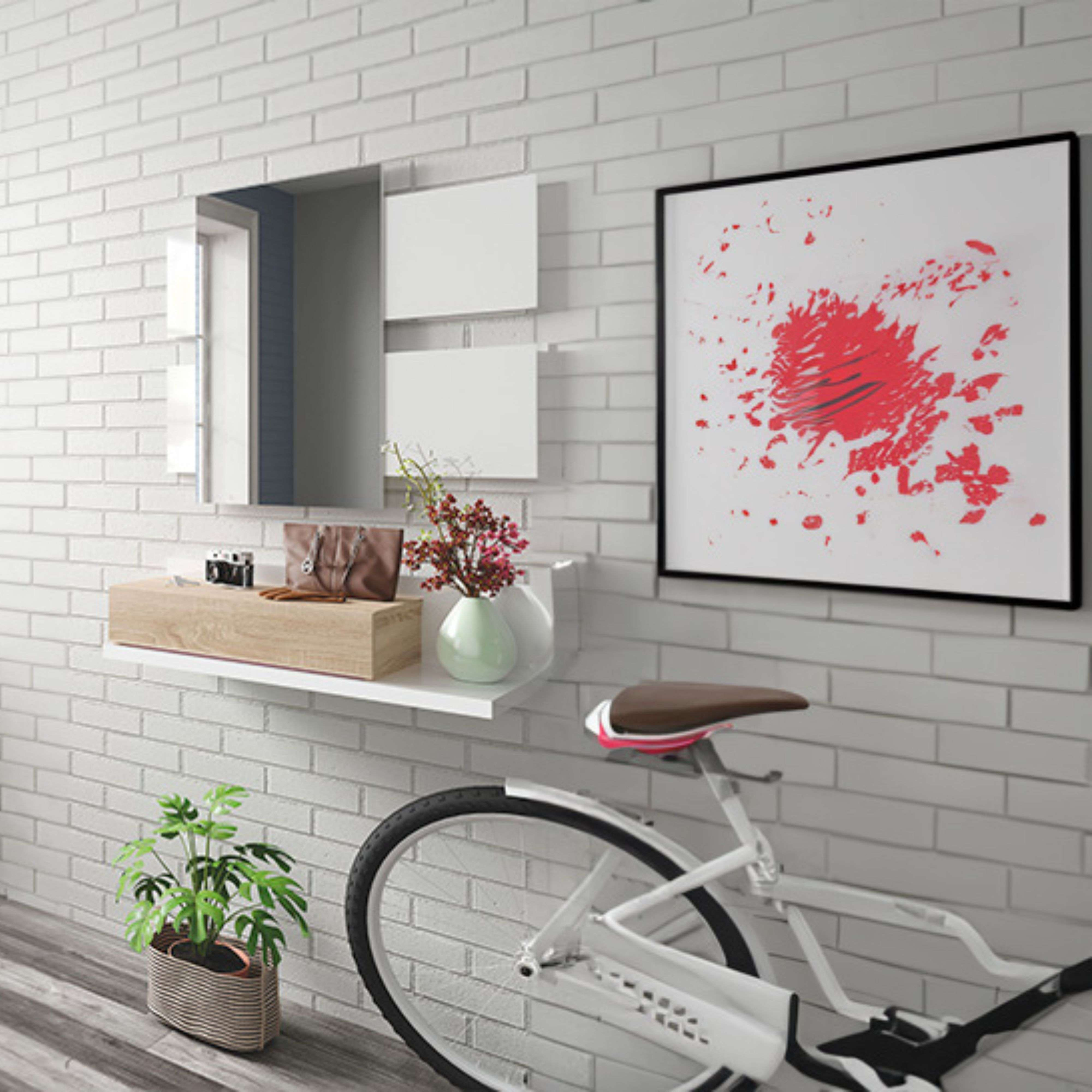 Una bicicleta está frente a una pared de ladrillos blancos con arte y un estante.