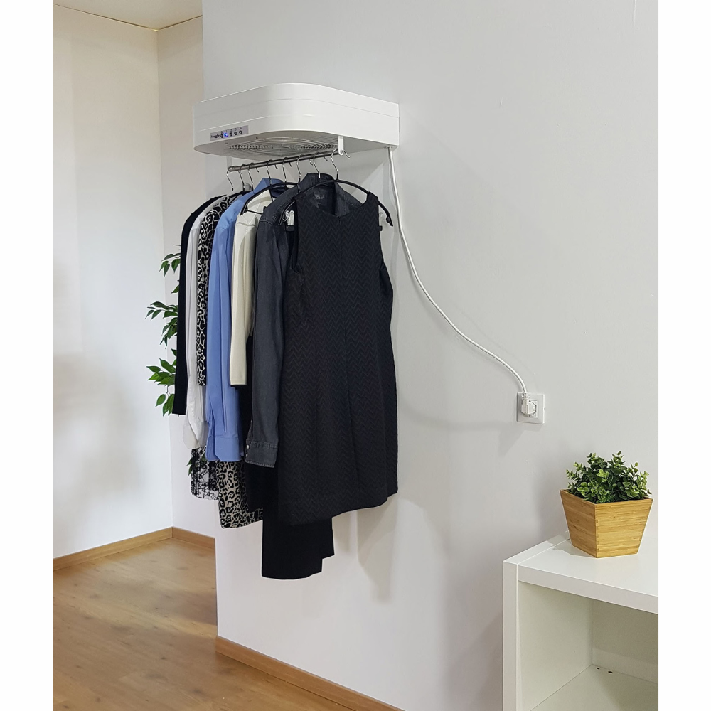 Uno stendibiancheria bianco a muro con vestiti appesi.