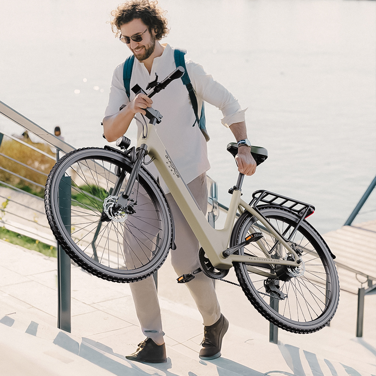 Mężczyzna niesie rower po schodach, morze w tle.