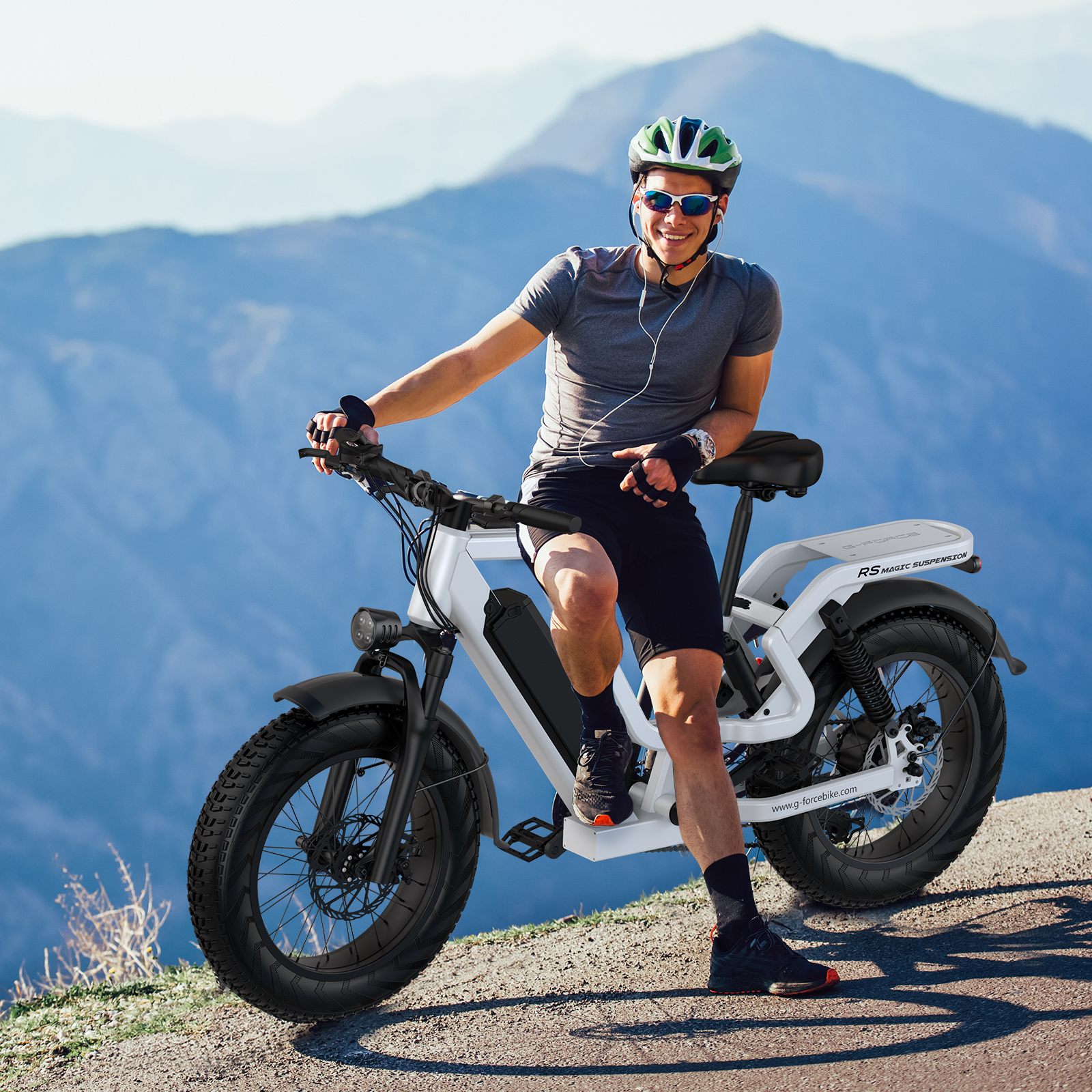 Mężczyzna siedzi na białym rowerze elektrycznym w górach, w kasku i okularach.