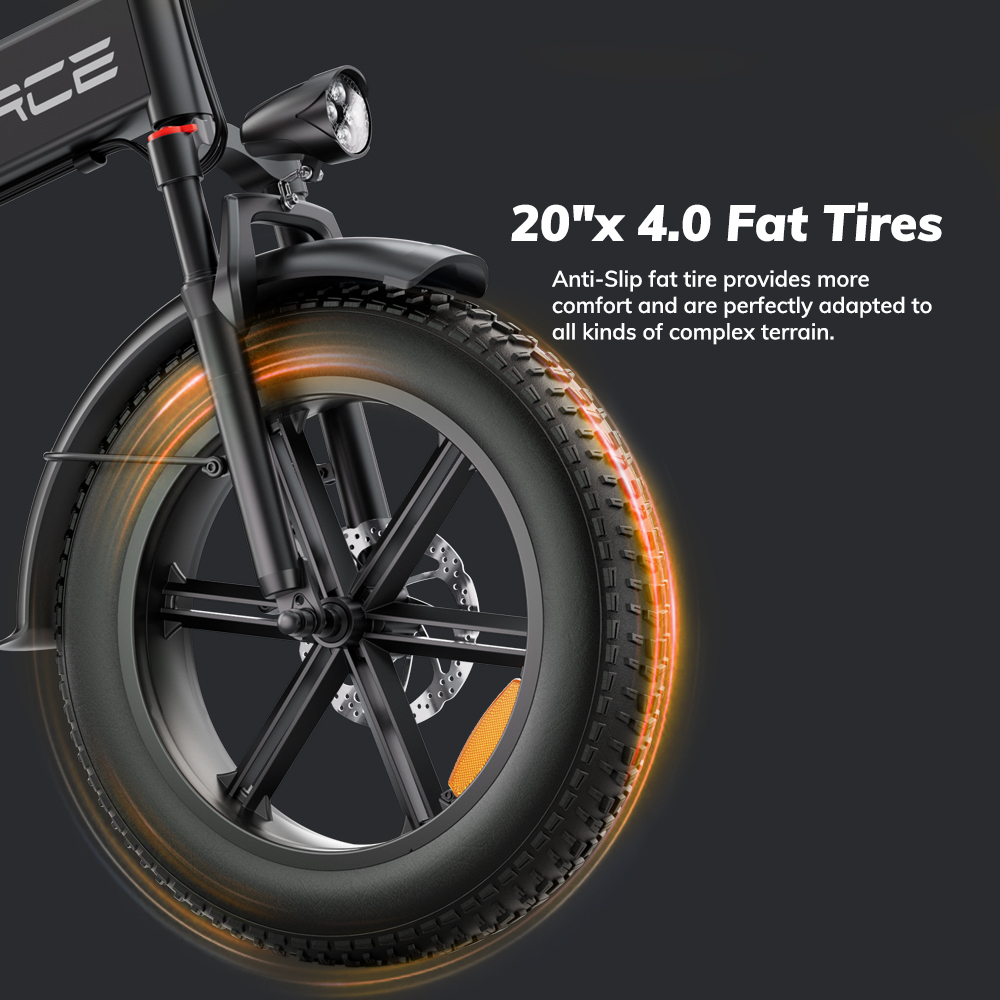 Zbliżenie czarnego koła roweru z grubymi oponami i pomarańczowym podświetleniem.