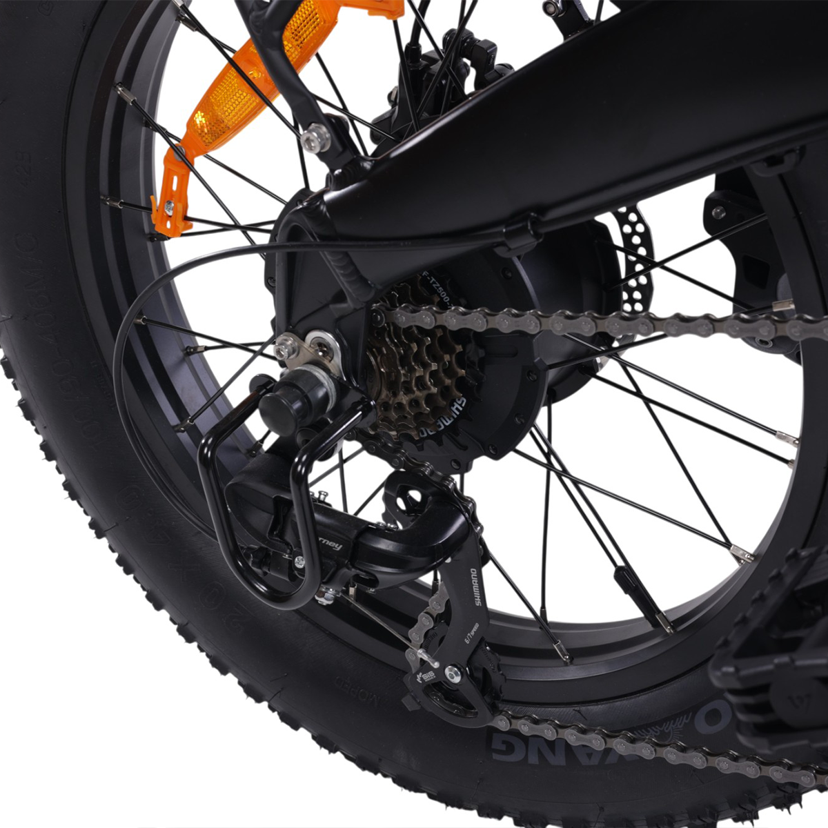 Zbliżenie tylnego koła czarnego roweru, pokazujące łańcuch i biegi.