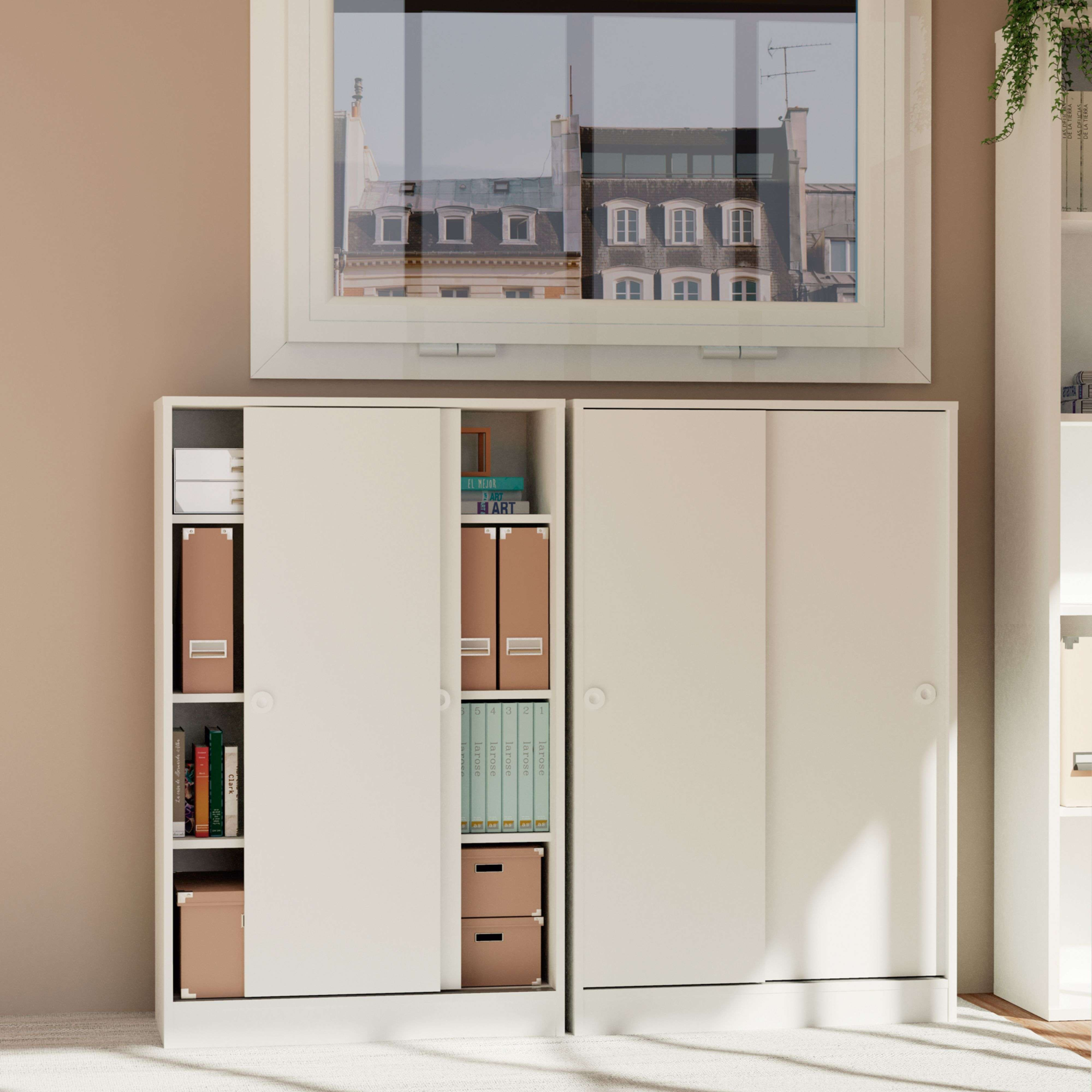 Una estantería blanca con libros, carpetas y cajas marrones contra una pared.
