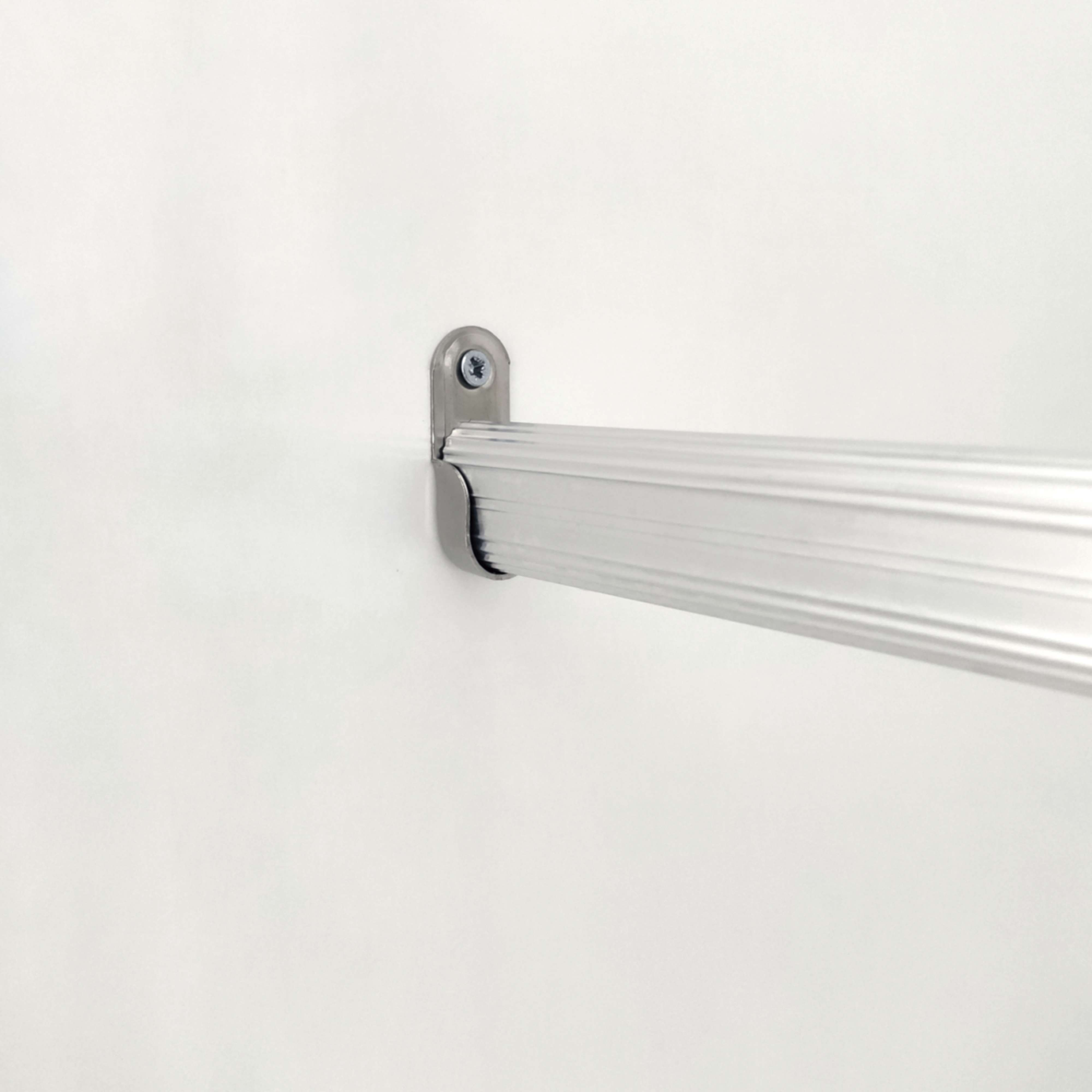 Una barra plateada sujeta un soporte metálico en una pared blanca.