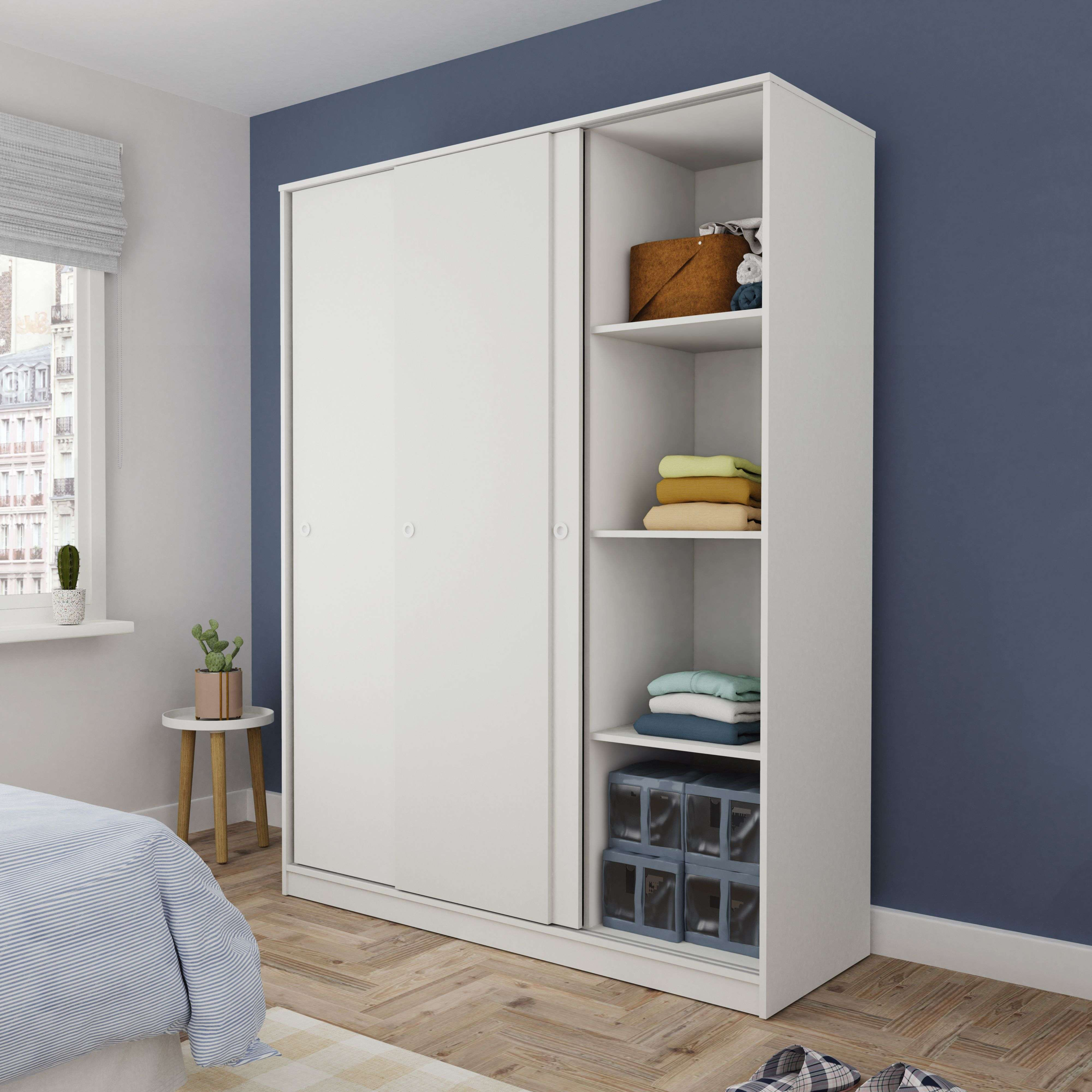 Un armario blanco con puertas correderas en un dormitorio con paredes azules.