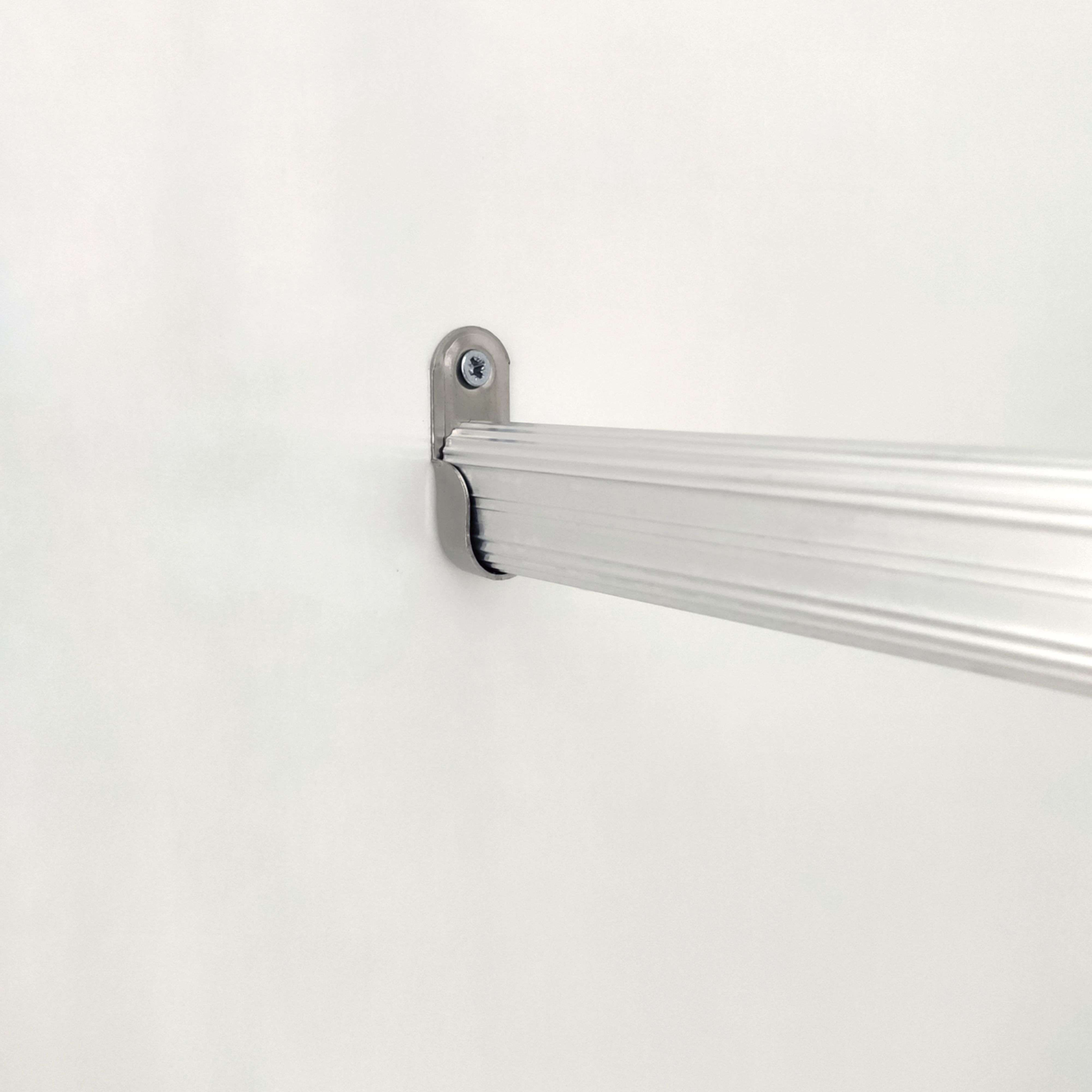 Una barra plateada acanalada sujeta por un soporte en una pared blanca.