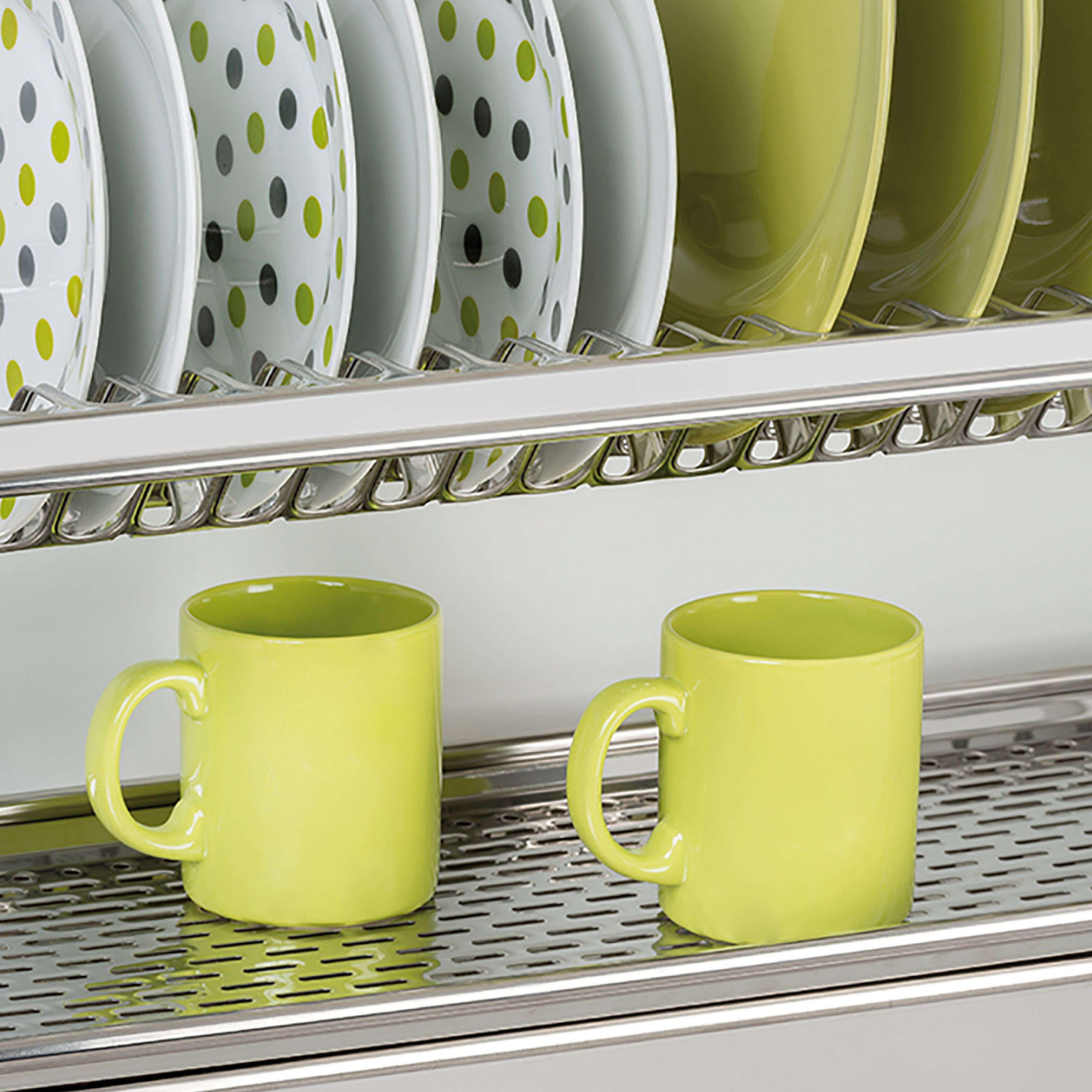 Dos tazas verde lima sobre un estante metálico, con platos detrás.