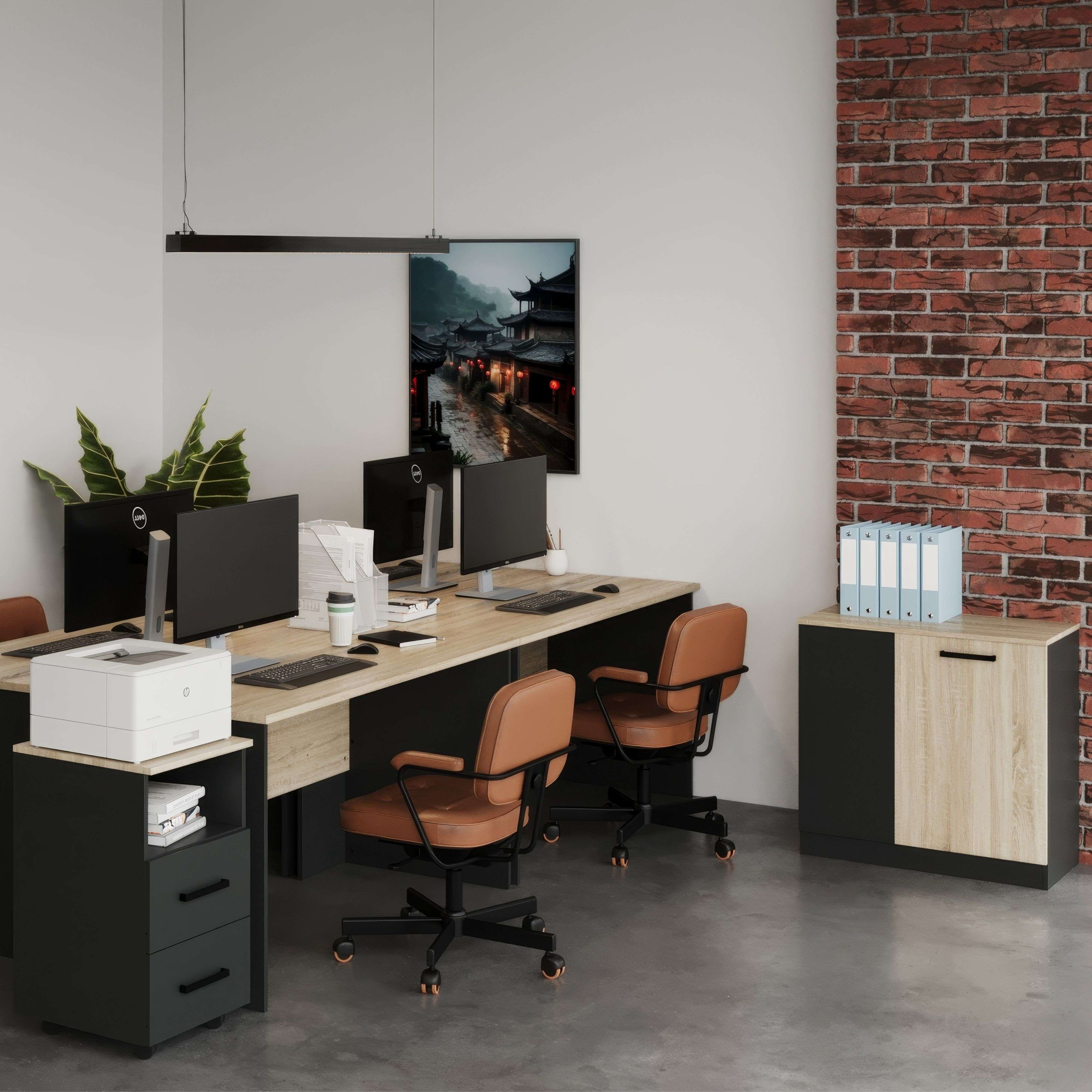 Oficina con escritorios, computadoras, sillas de cuero marrón y pared de ladrillos.
