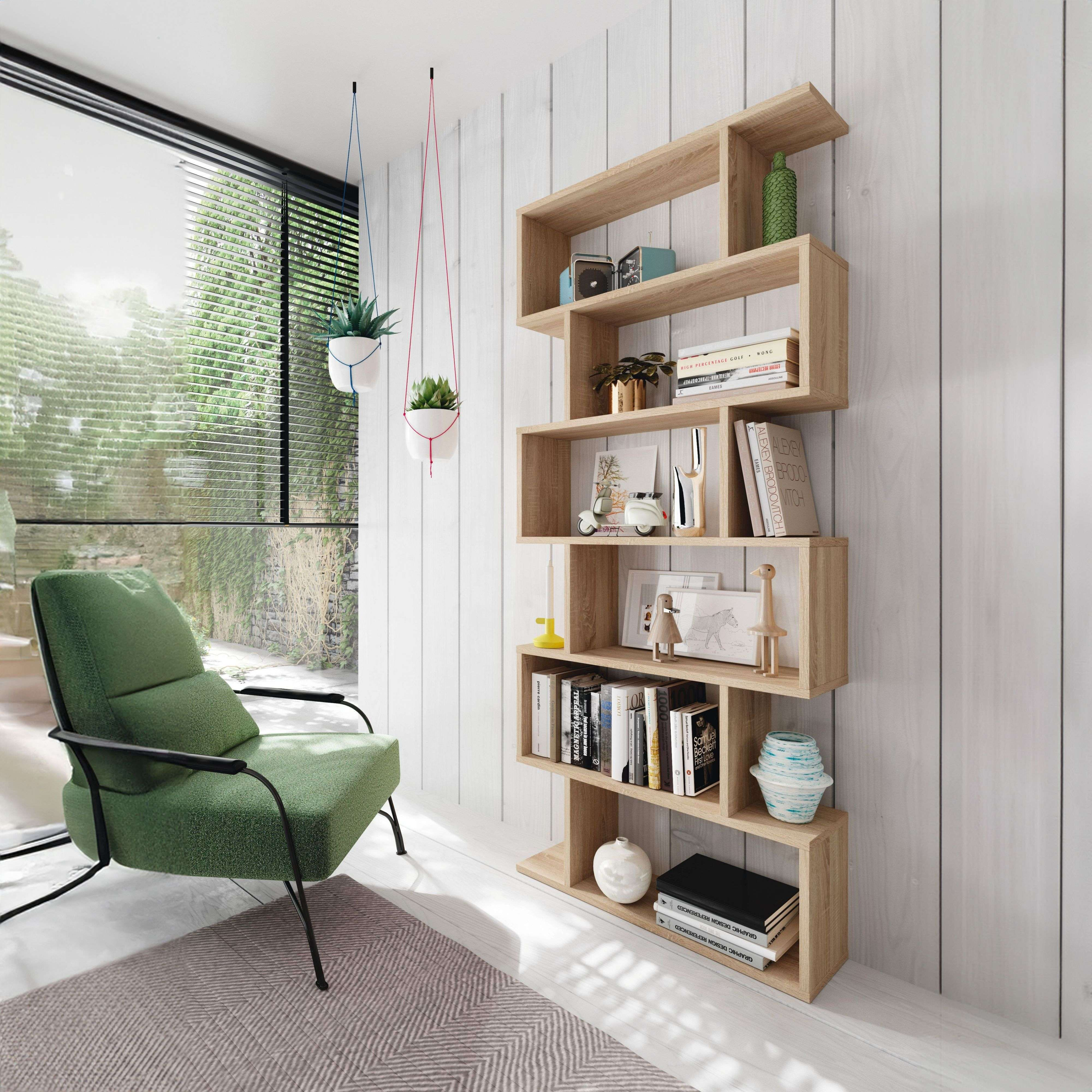 Un sillón verde junto a una estantería de madera con libros y adornos.