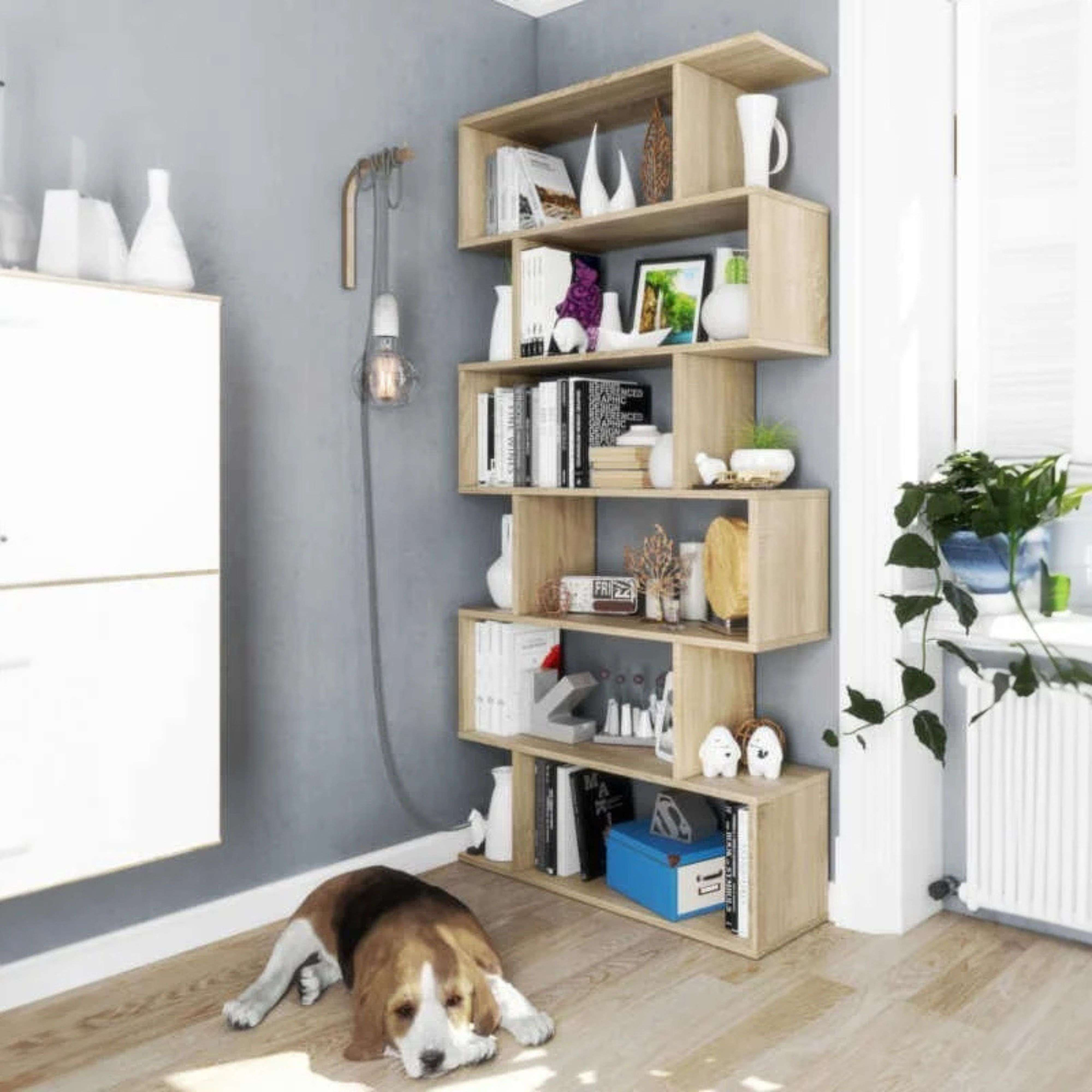 Un beagle yace en un suelo de madera frente a una estantería con libros y decoración.