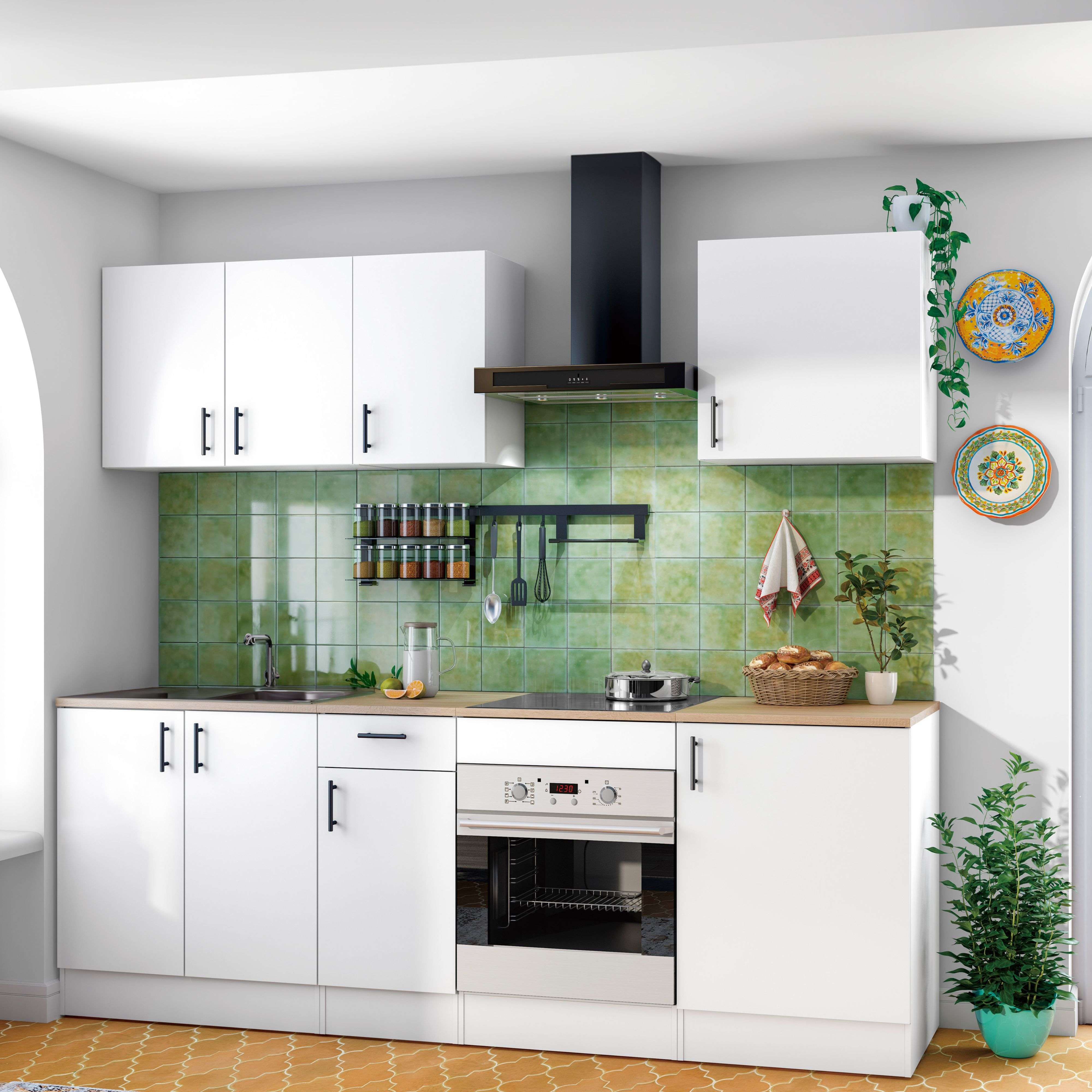 Una cocina blanca con azulejos verdes, horno, placa y decoración.