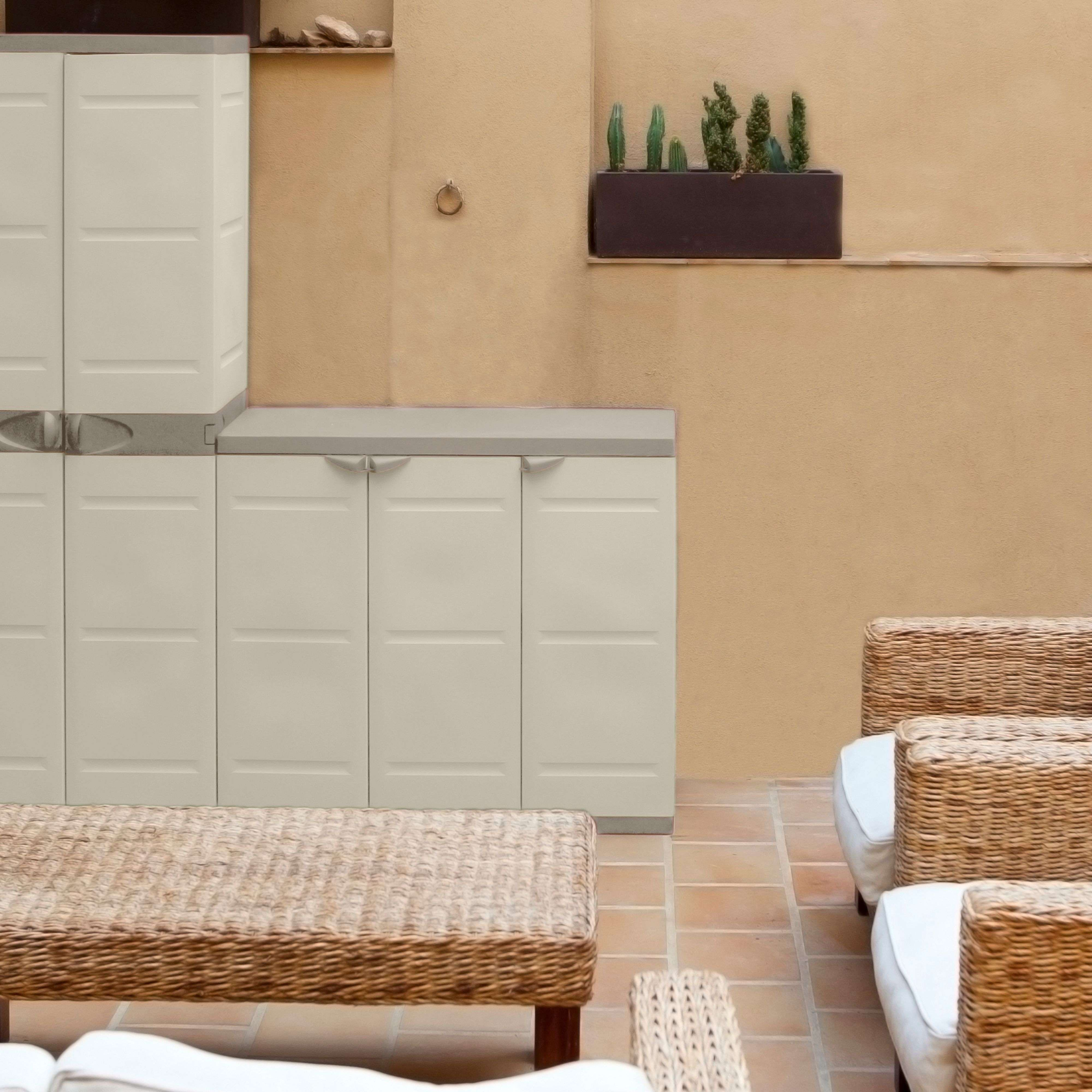 Armarios claros y muebles de mimbre en un patio con baldosas de terracota.