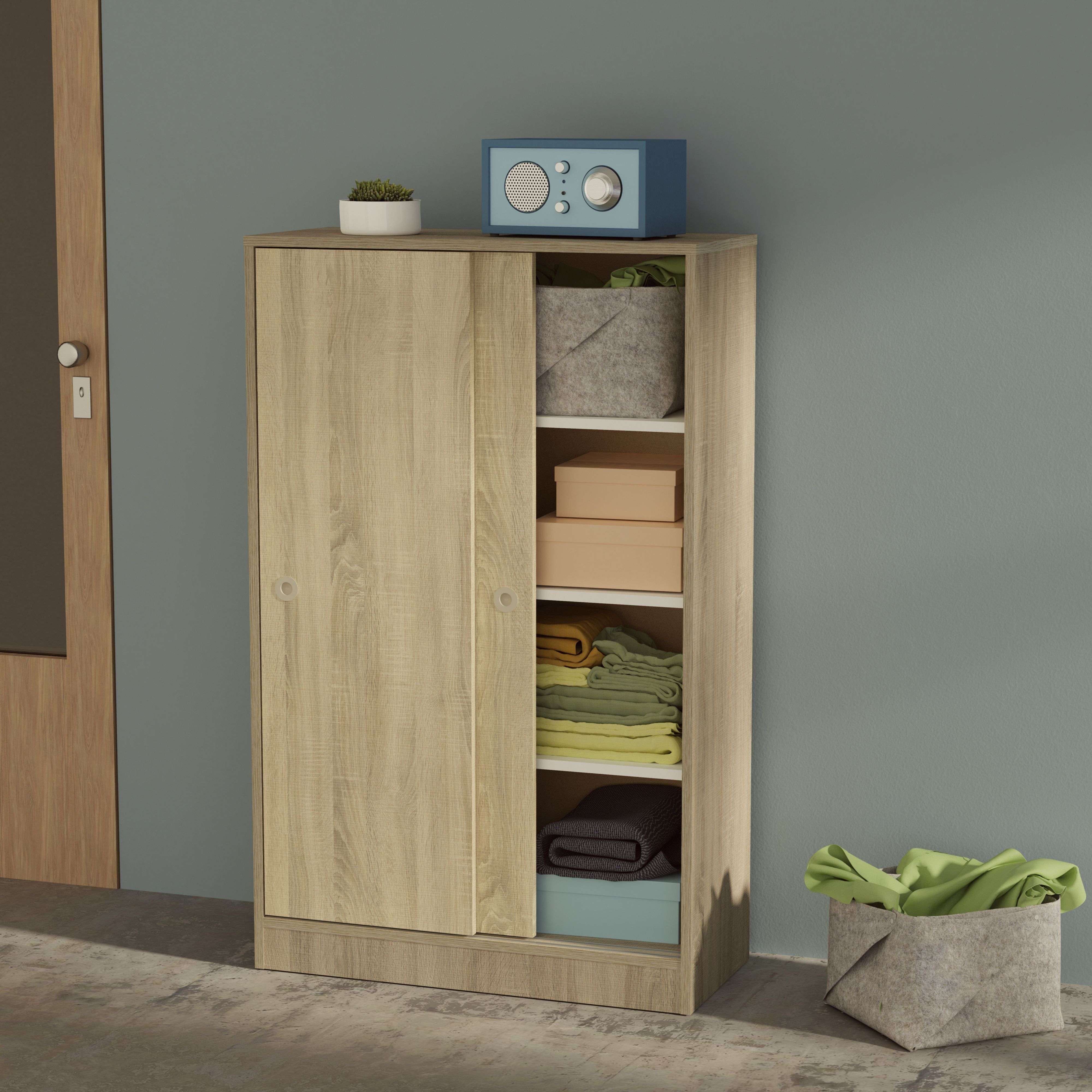 Un armario de madera con puertas correderas, lleno de textiles doblados y cajas.