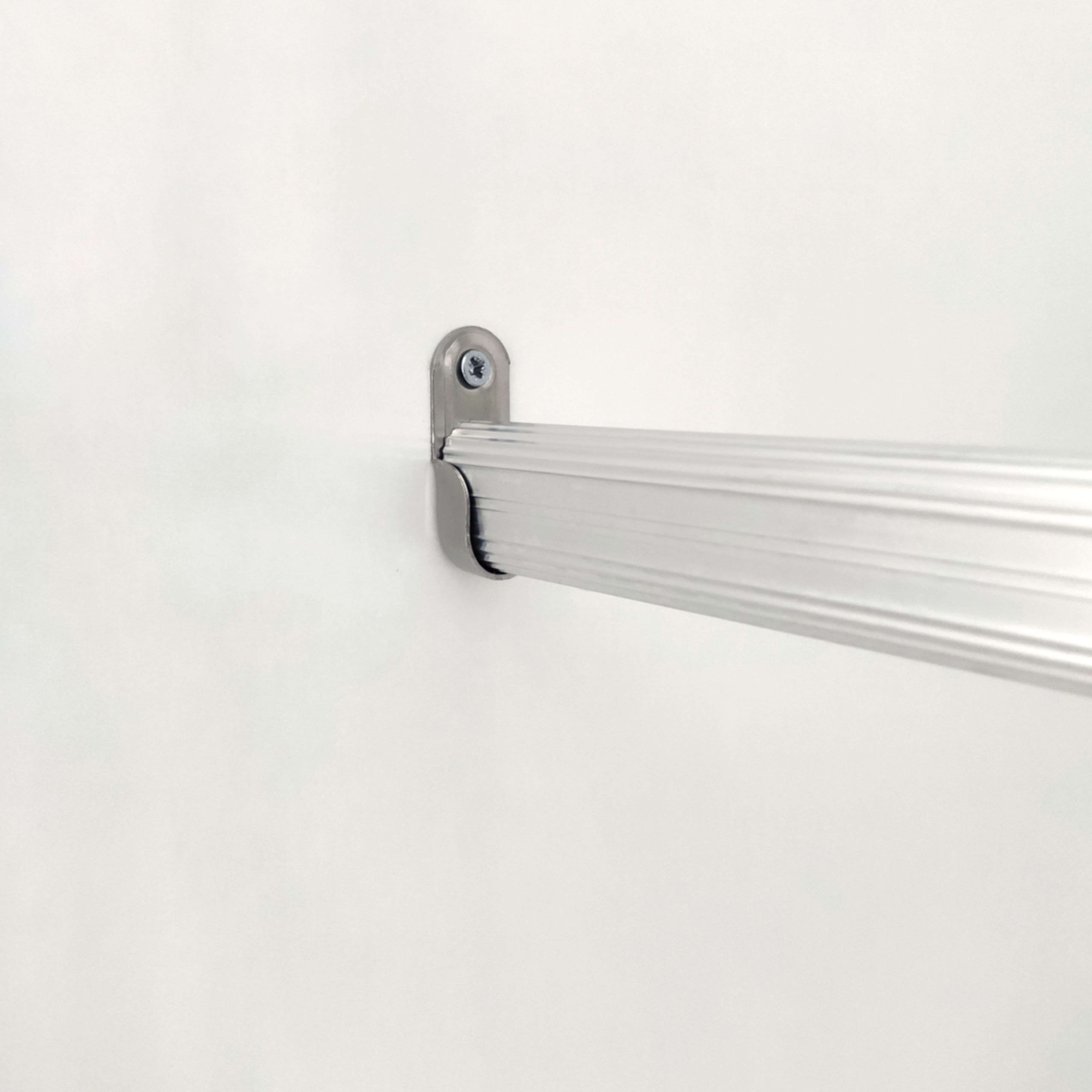 Una barra de aluminio plateada sujeta a una pared blanca.