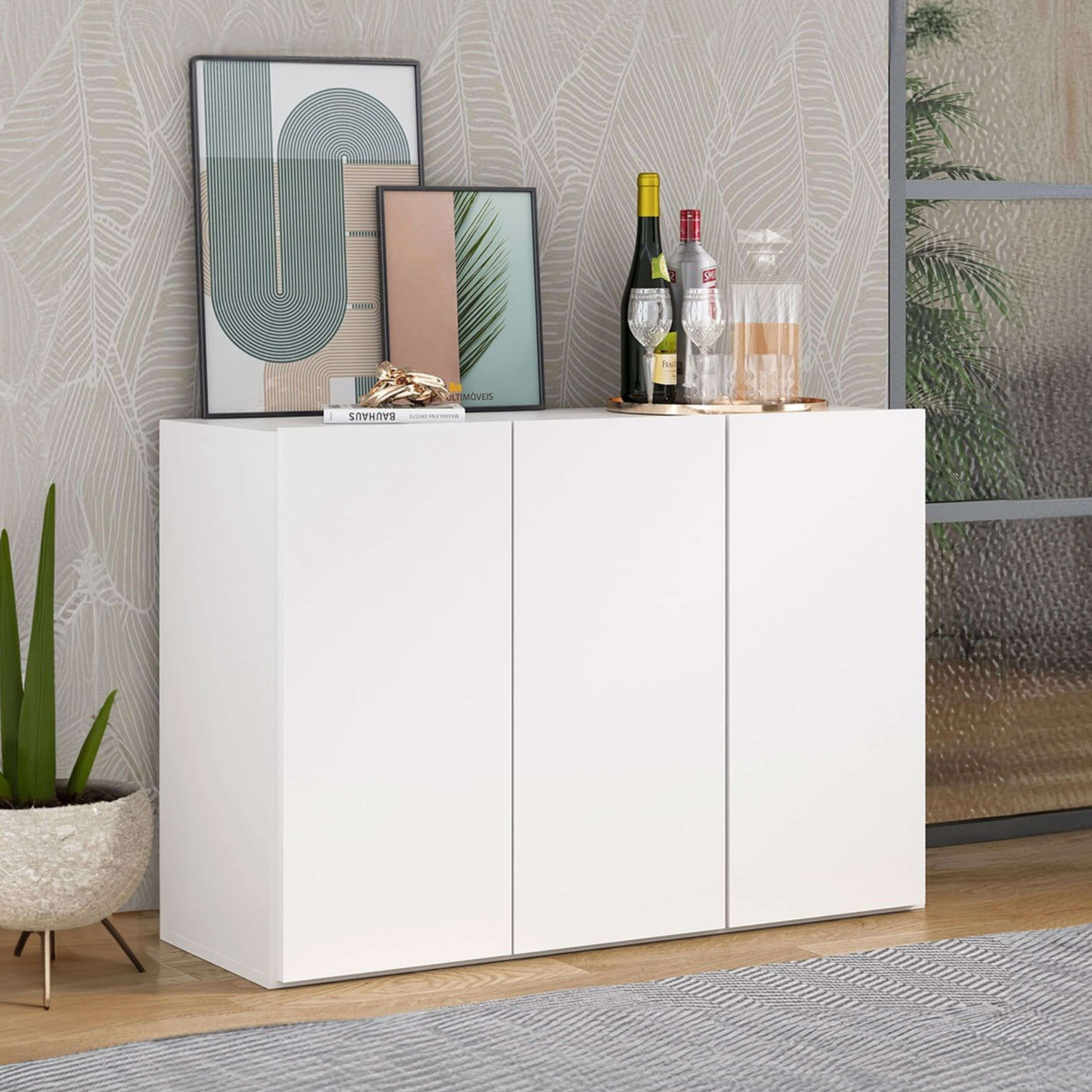 Un aparador blanco de tres puertas decorado con cuadros y botellas.