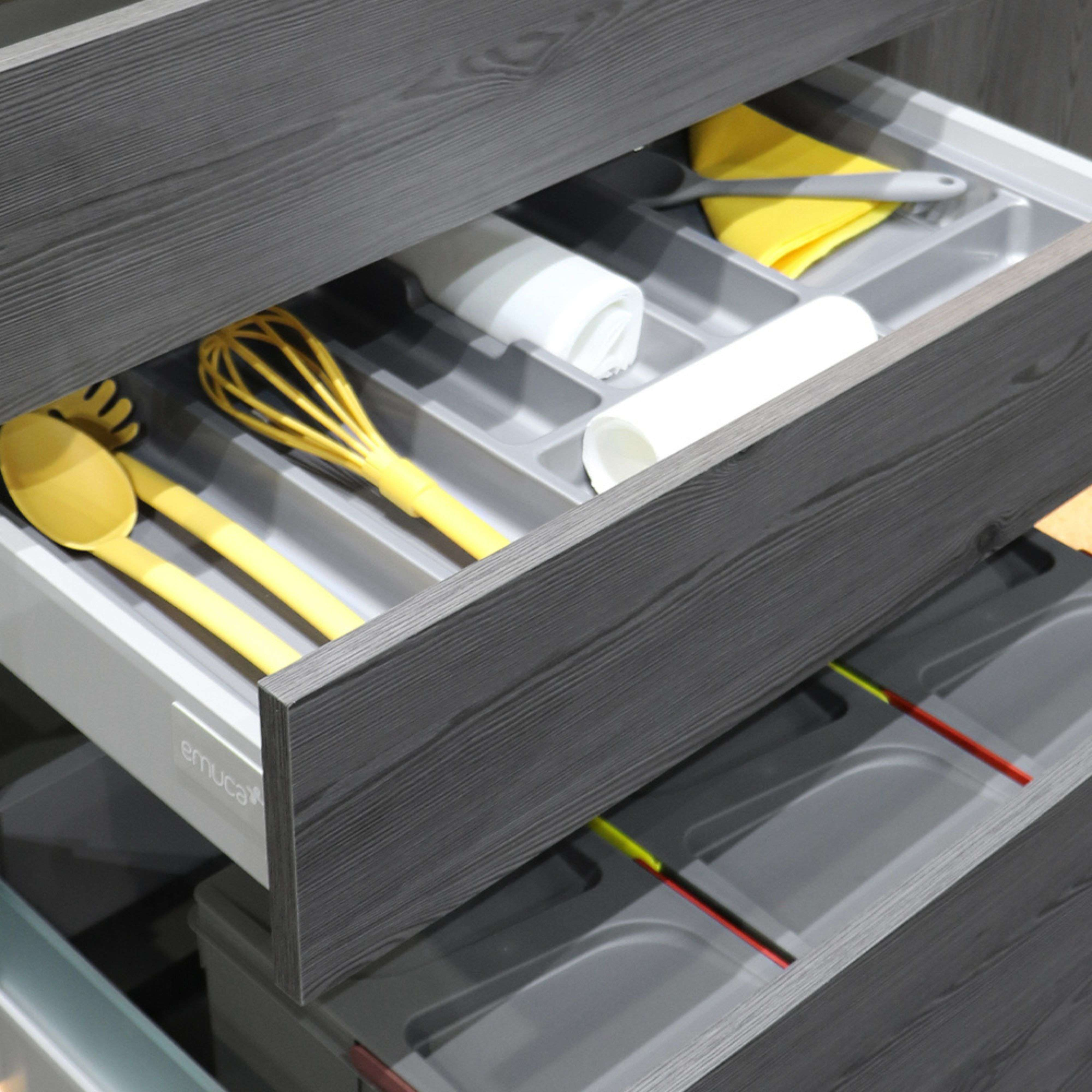 Cajón de cocina con utensilios: batidor amarillo, cucharas y toallas.