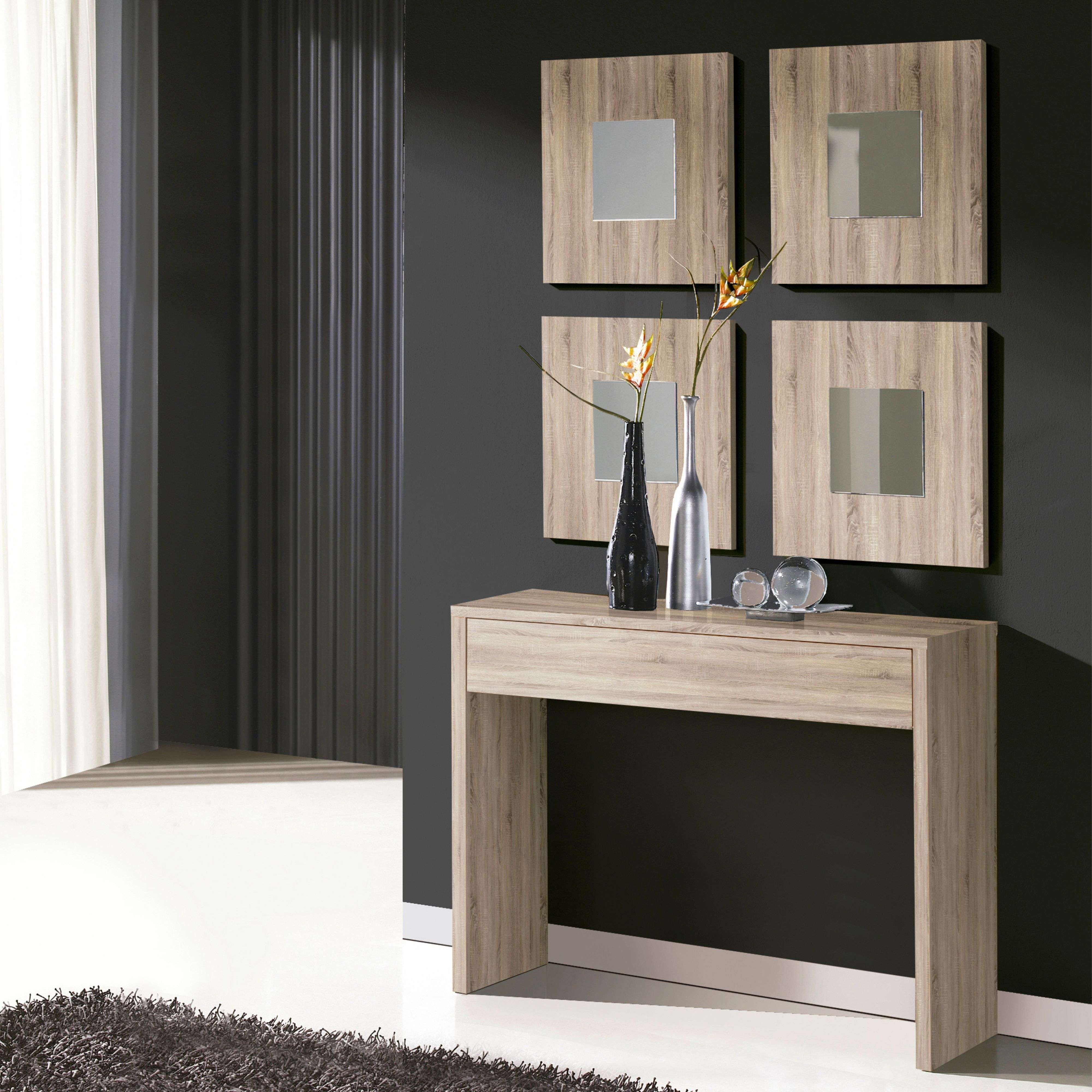 Una mesa estrecha de madera se alza ante una pared oscura con cuatro espejos cuadrados.