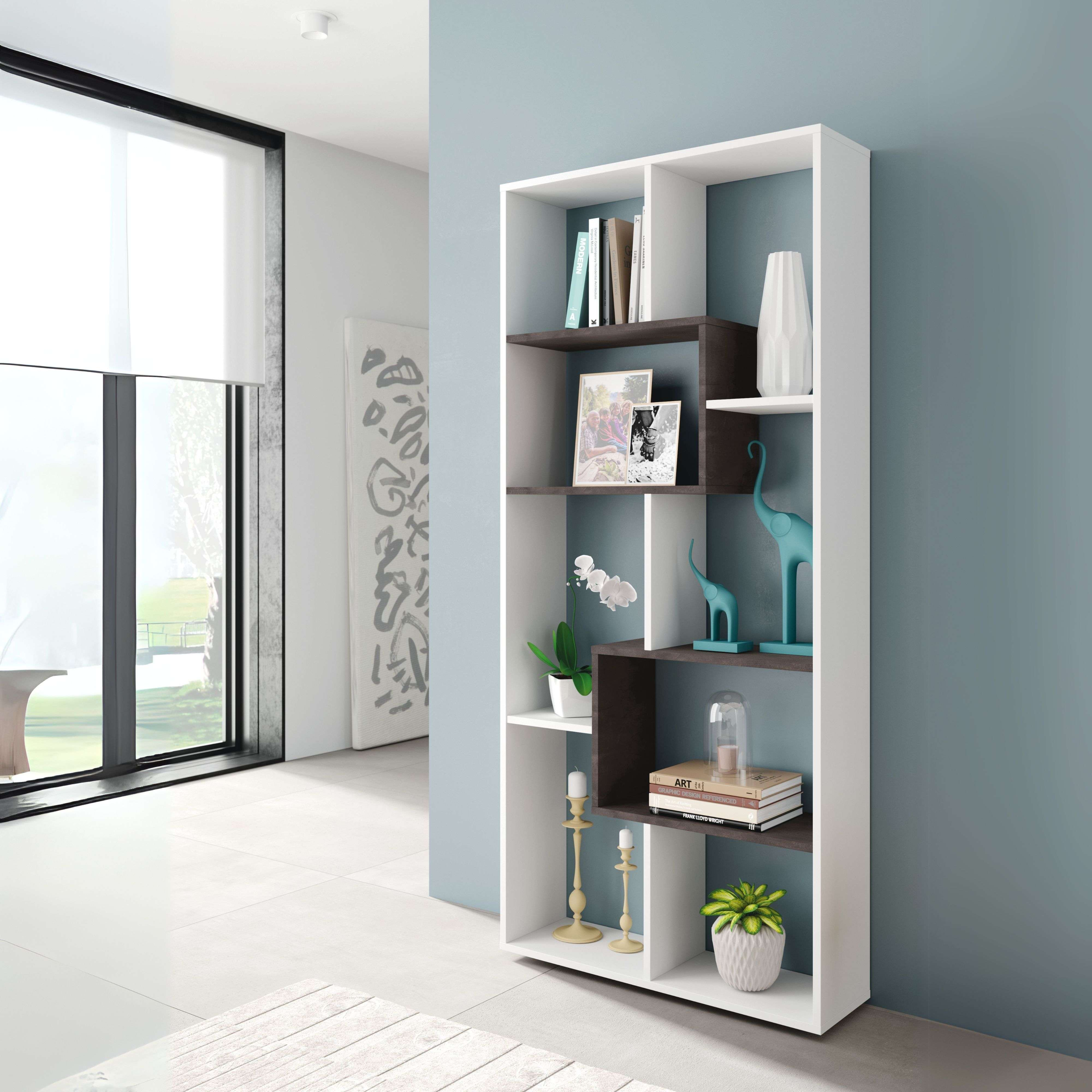 Una estantería blanca con libros, jarrones, fotos y decoraciones contra una pared azul.