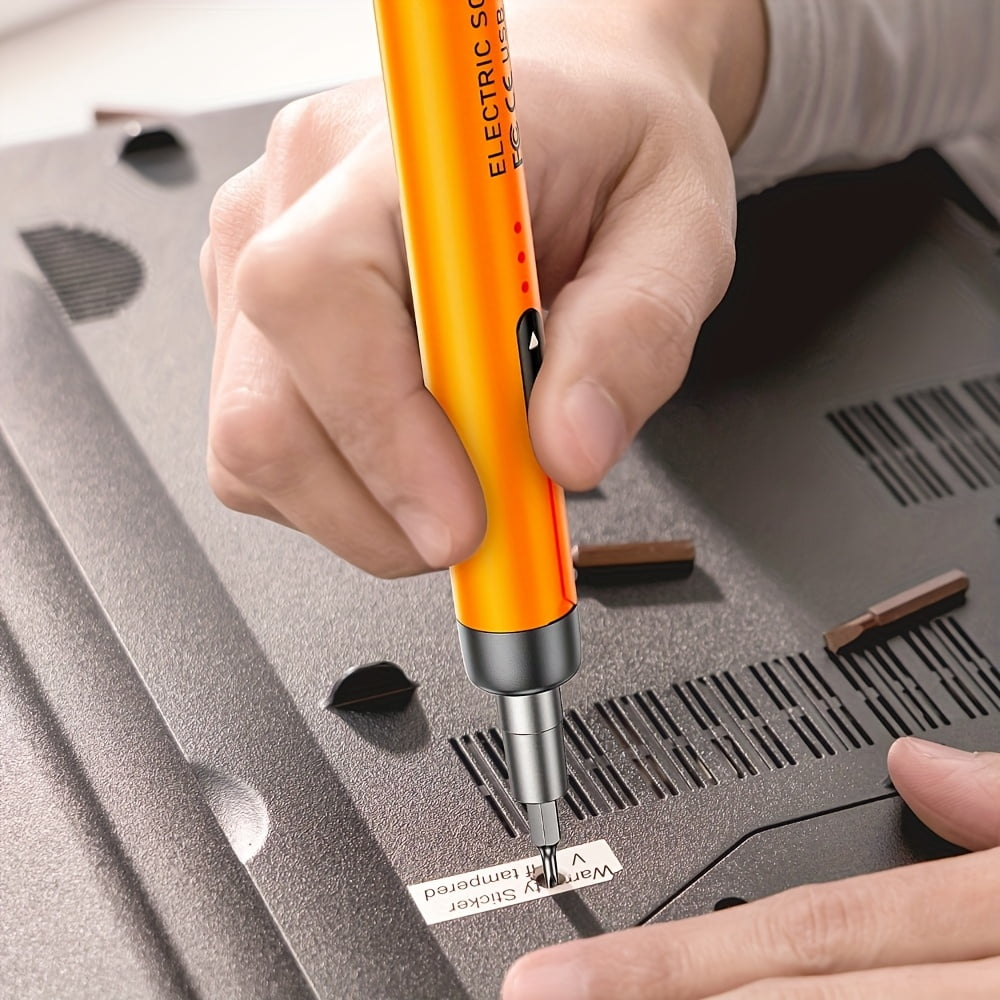 Person benutzt einen orangen elektrischen Schraubendreher an der Unterseite eines Laptops.