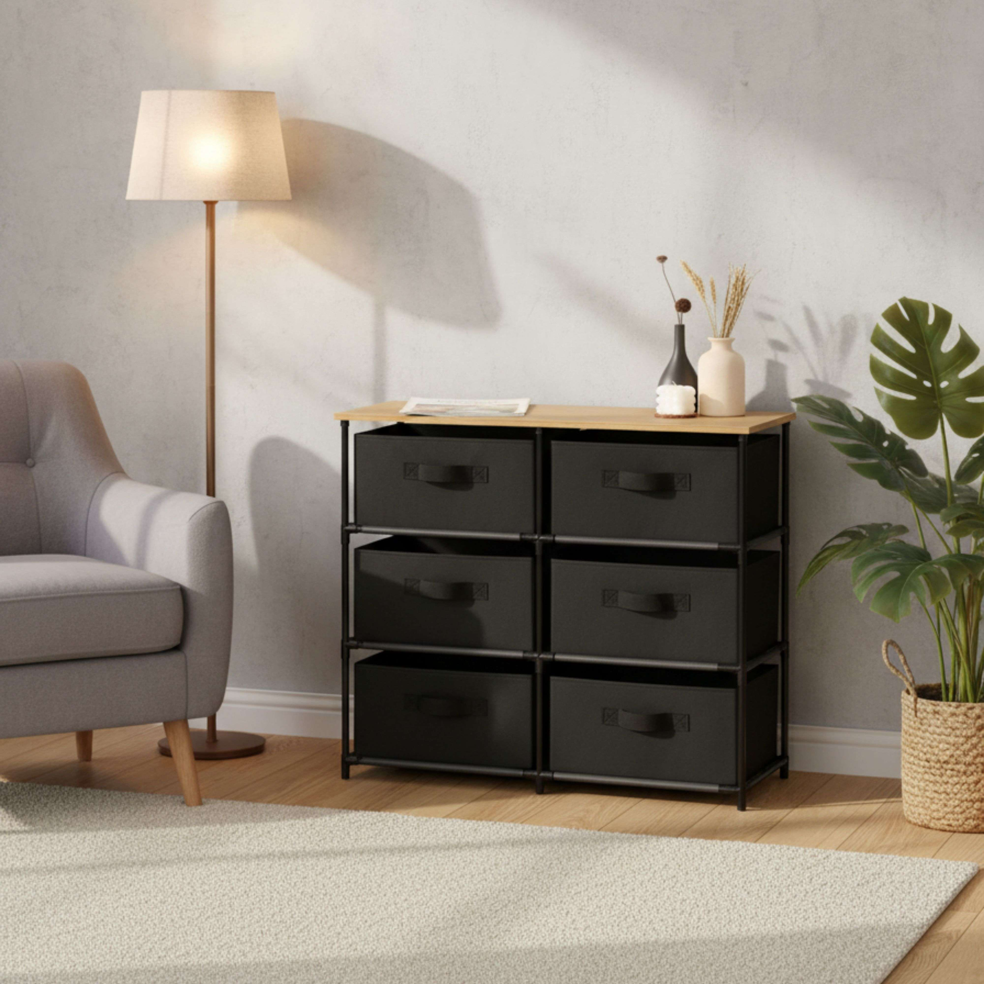 Un sillón gris, un pie de lámpara de pie, una cómoda de tela con seis cajones y una planta.