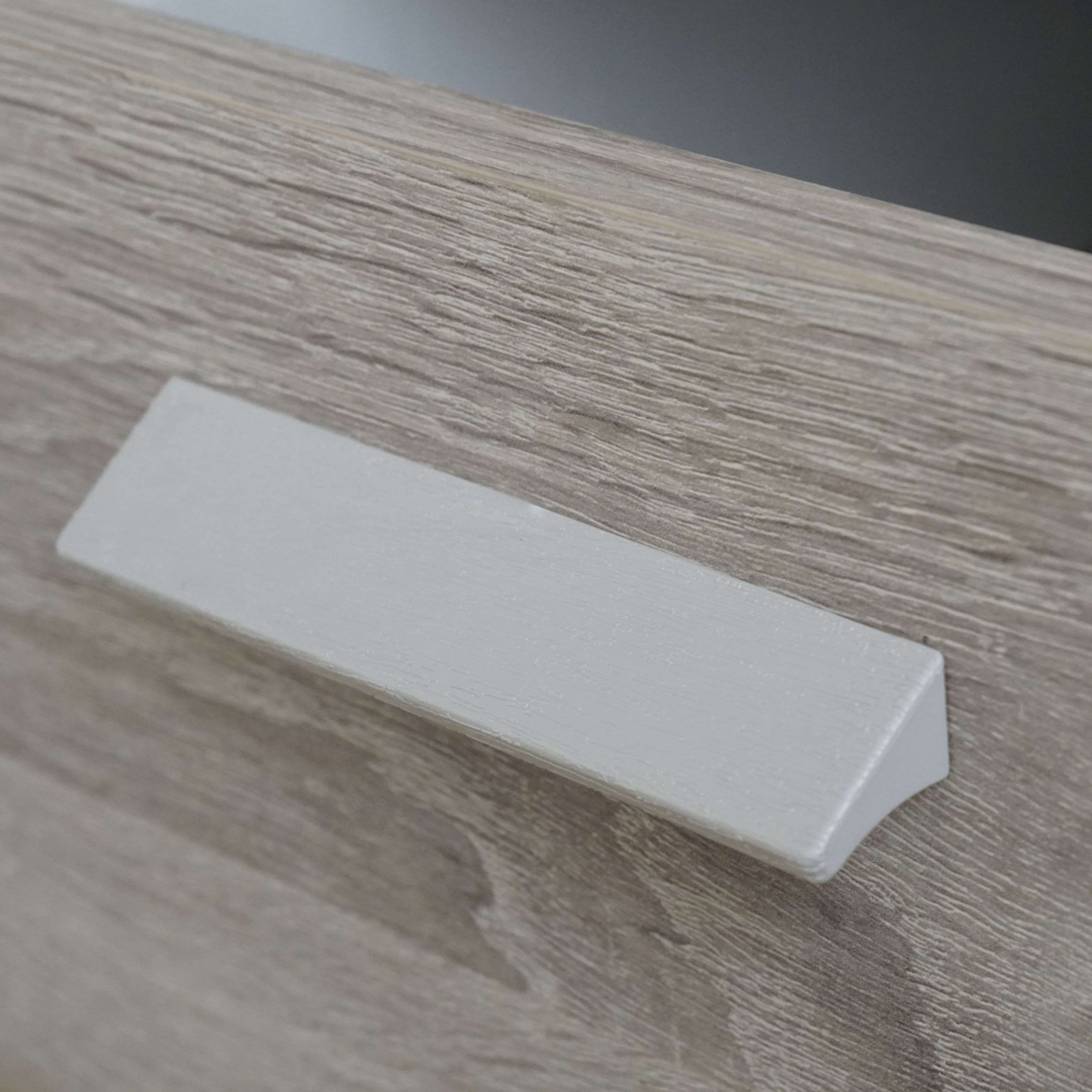 Un tirador gris sobre una superficie de veta de madera.